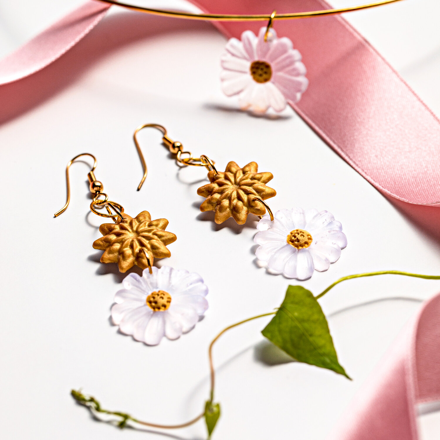 FIMO Liquid ofenhärtendes Modelliergel transparent, ideal für filigrane Schmuckstücke wie Ohrringe mit Blumenmotiv, präsentiert auf rosa Band.