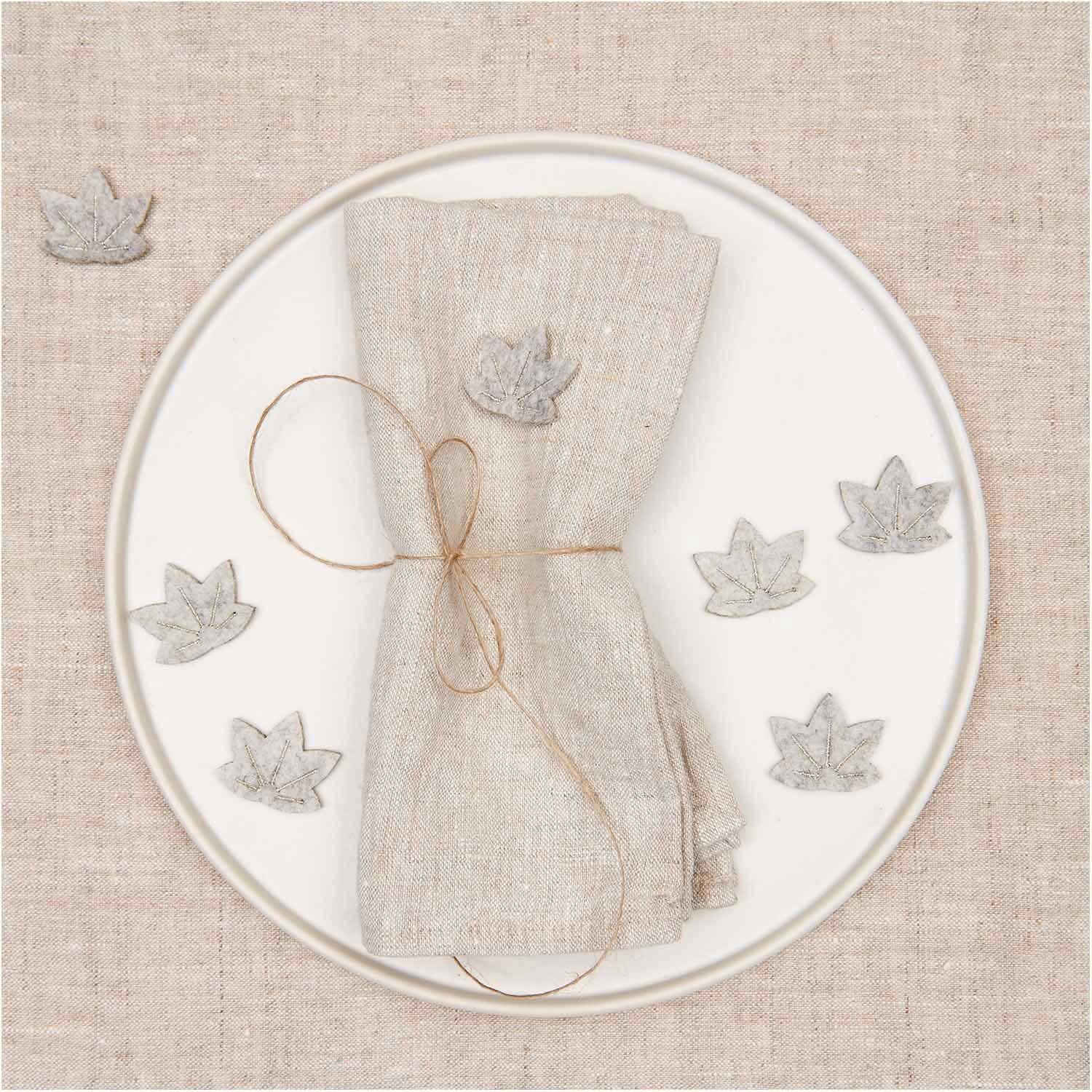 Filzstreu Ahornblatt grau-gold 12 Stück dekoriert einen Teller mit Serviette, ideal für Herbstdeko.