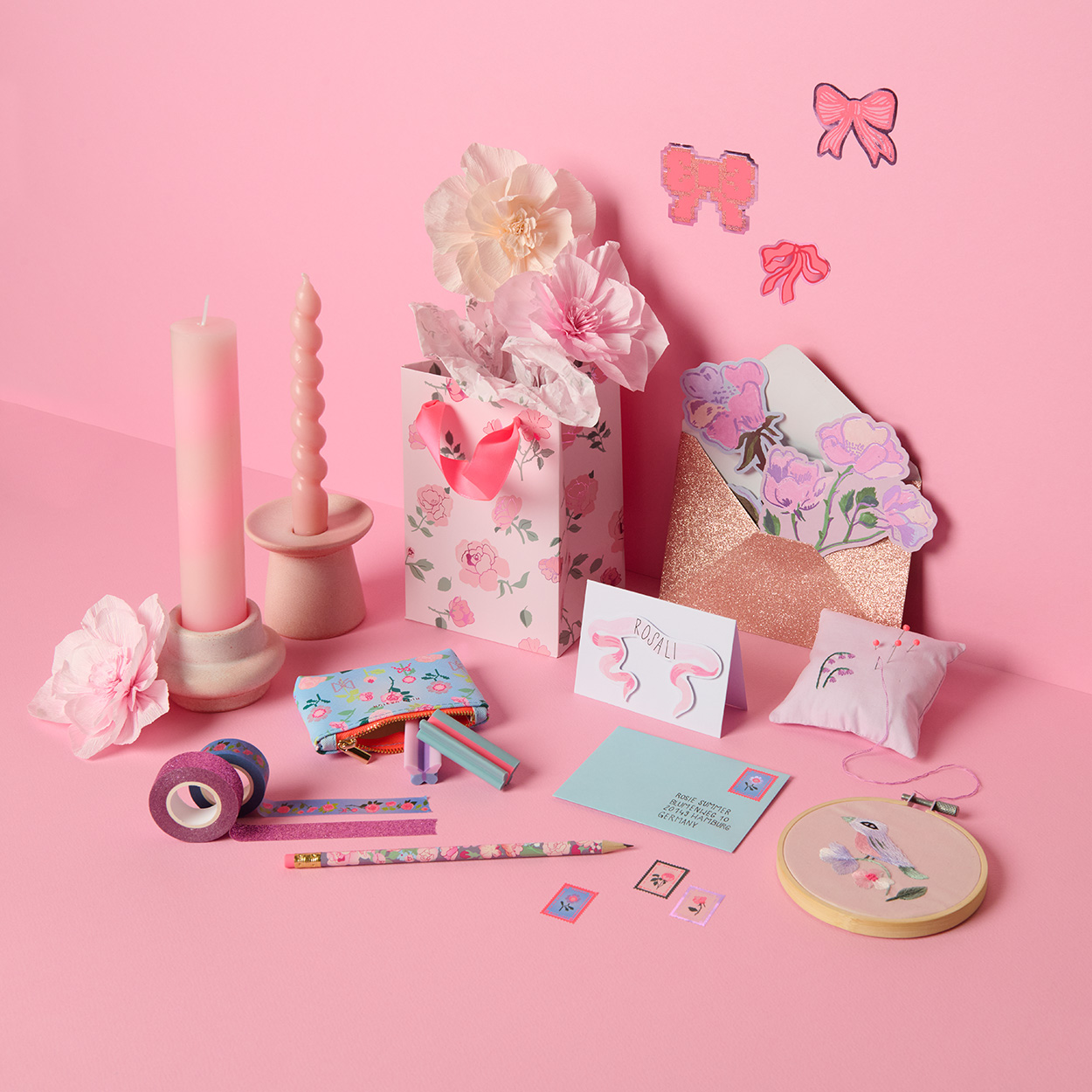 Papiertüte, Karten, Tapes, Stifte und Kerzen in rosa Farben mit Blumen- und Schleifen-Design. Fotosetting pinke Ecke.