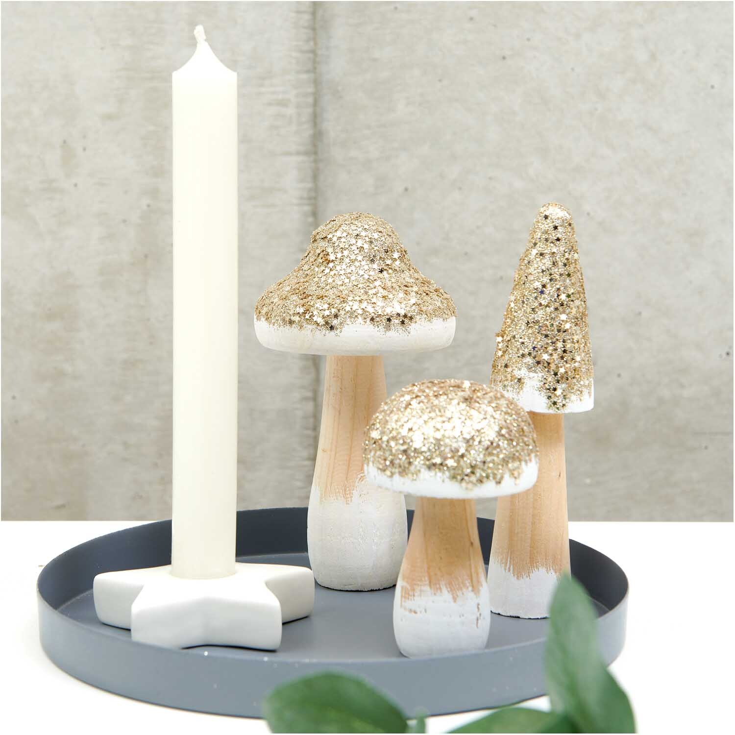Holzpilz mit Glitter gold: Dekorative Pilze in Naturtönen mit glitzerndem Goldakzent auf grauem Tablett.