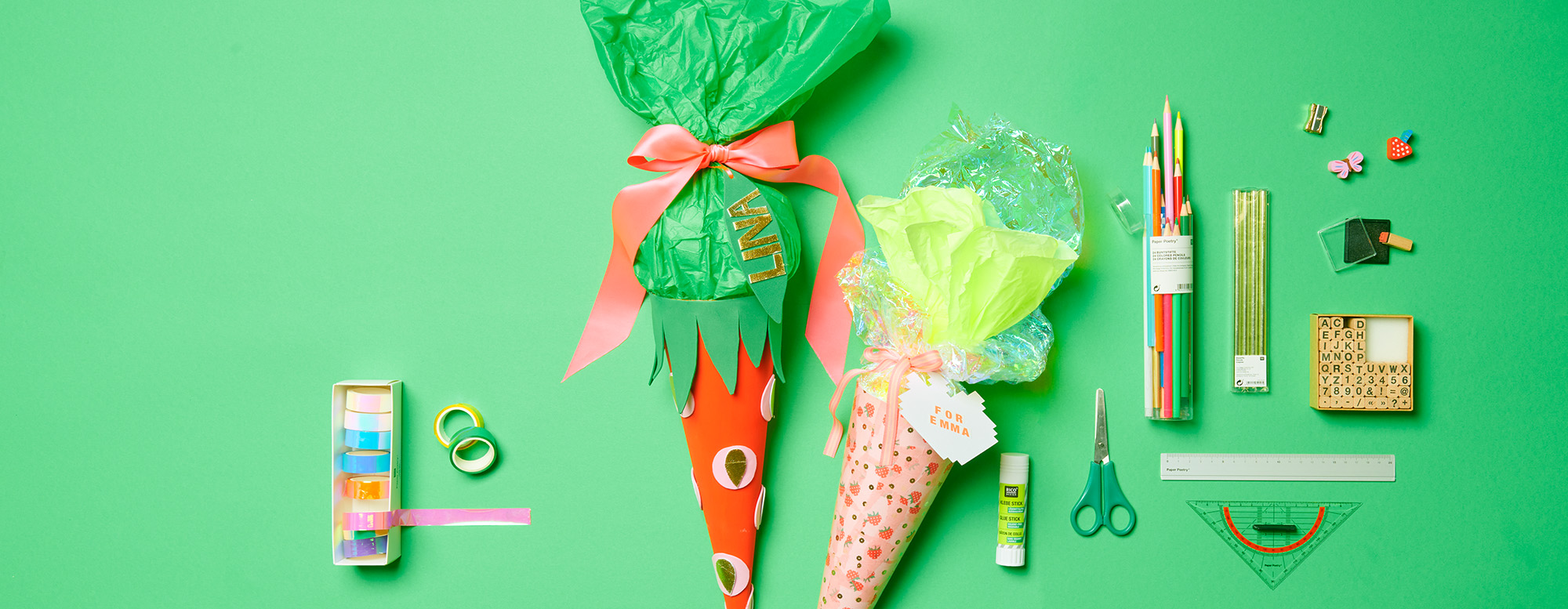 Schultüten in Erdbeer-Design mit Buntstiften, Lineal, Stempel, Radiergummis und bunten Tapes. Flatlay von Produkten.
