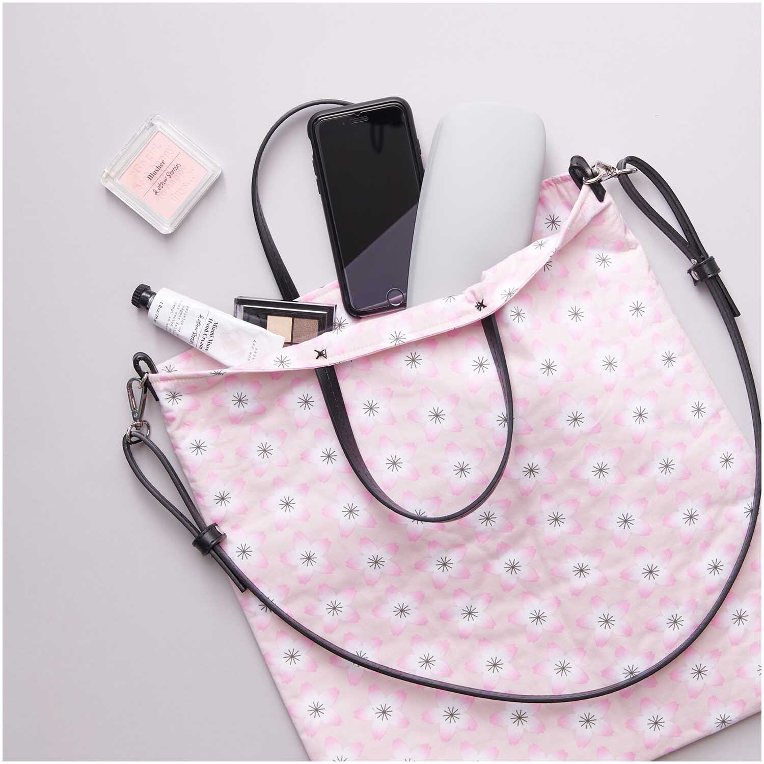Kunstleder Schulterriemen kurz schwarz-silber, passend für eine rosa Tasche mit Blumenmuster, umgeben von Alltagsgegenständen.