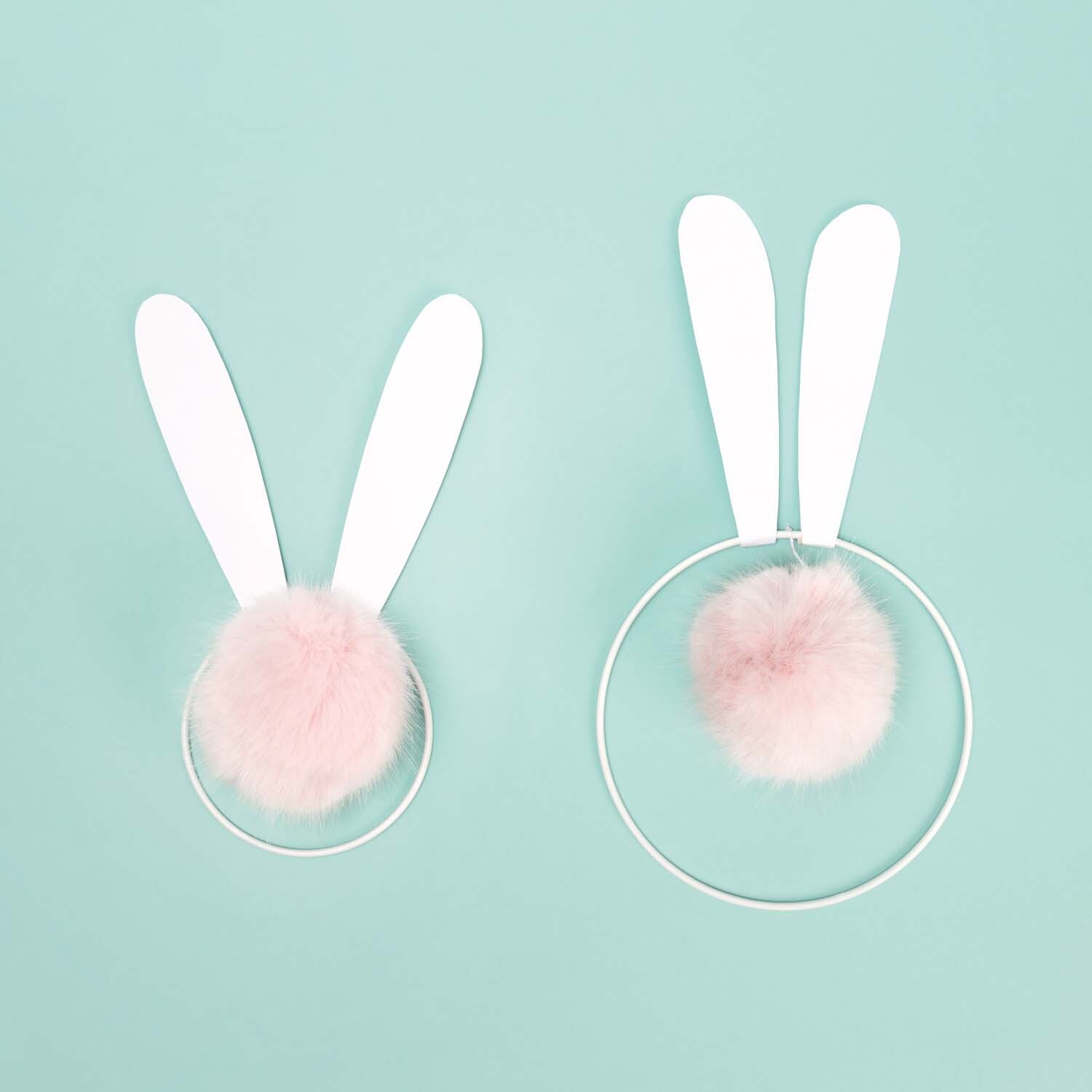 Bastelanleitung Plüschhasen als Wanddeko: Zwei Hasenohren aus Papier und rosa Plüschbommeln auf mintgrünem Hintergrund.