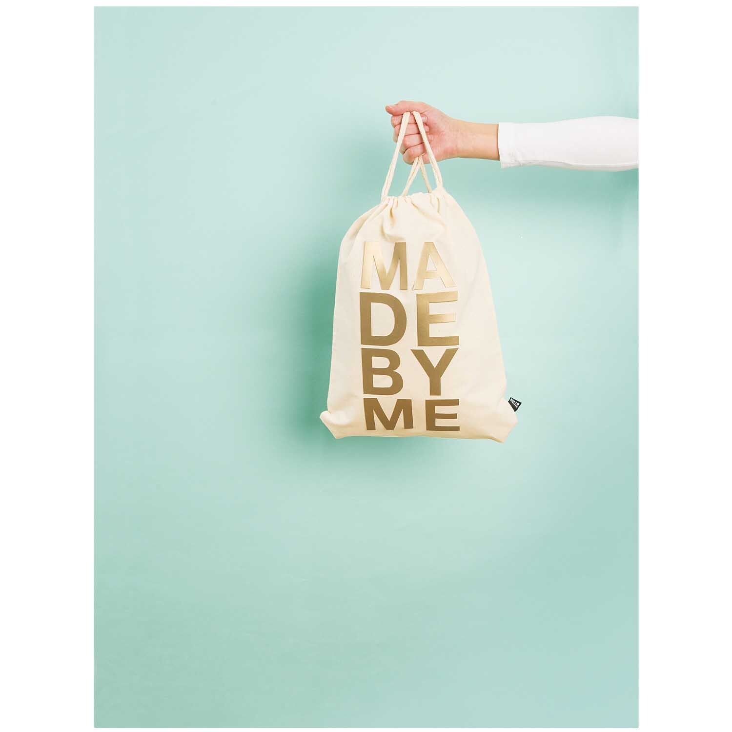 Rucksackbeutel aus Naturstoff, 35x42,5cm, von Rico Design, wird von einer Hand vor mintgrünem Hintergrund gehalten.