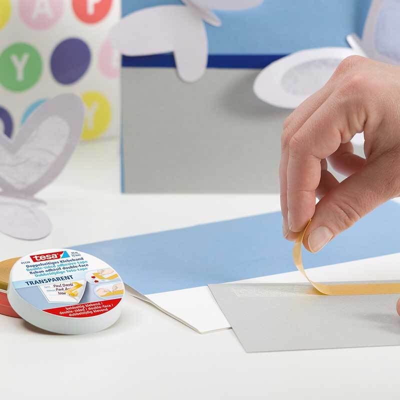 Doppelseitiges Klebeband 15mm 10m wird von einer Hand auf Papier aufgetragen, ideal für Bastelarbeiten.