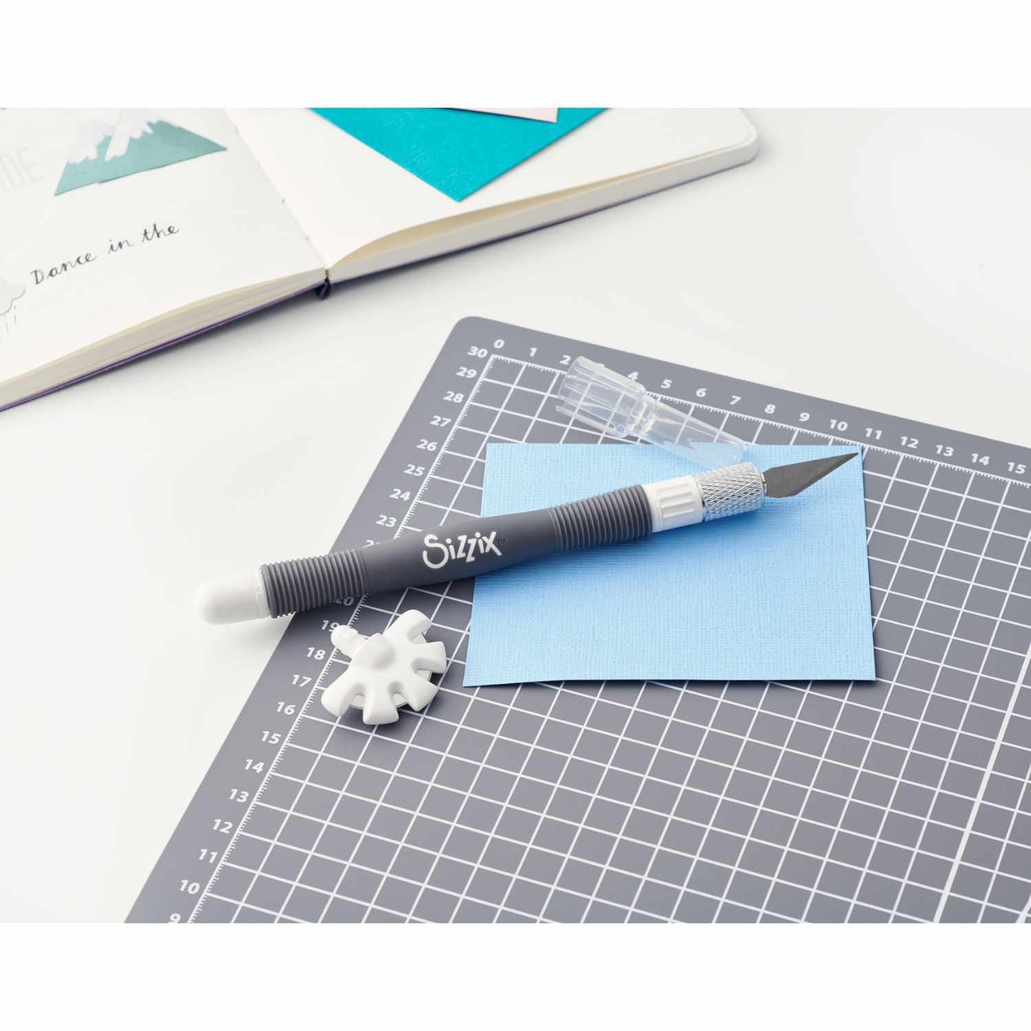 Making Tool Multi Tool von Sizzix auf einer Schneidematte mit blauem Papier und Ersatzklinge.
