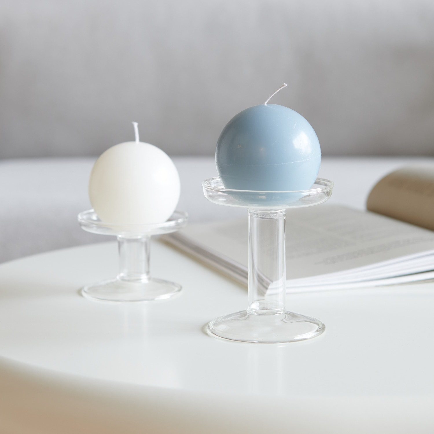 Kugelkerze von Rico Design in Blau auf einem Glasständer, dekorativ auf einem Tisch platziert.