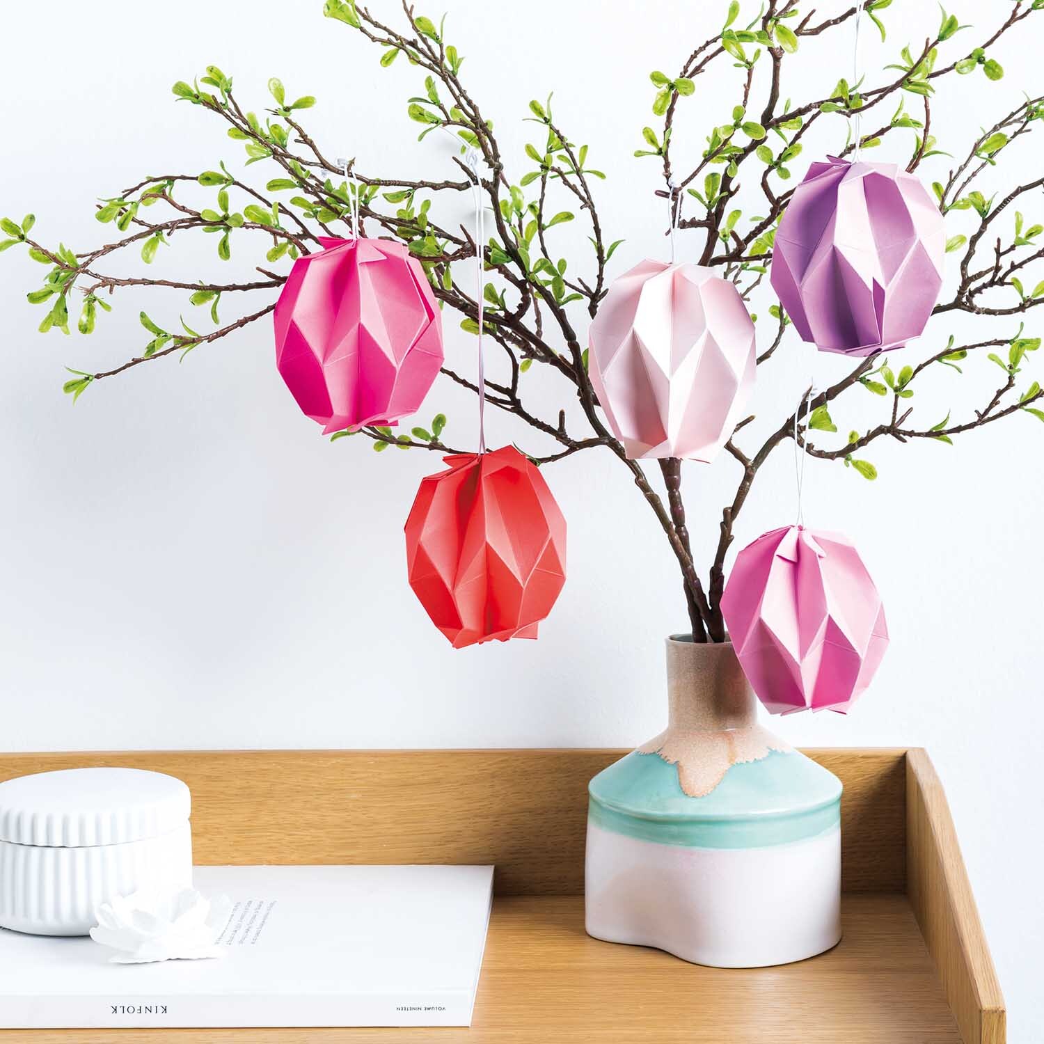 Bastelanleitung grafische Ostereier falten: Bunte, gefaltete Ostereier an Zweigen in Vase.