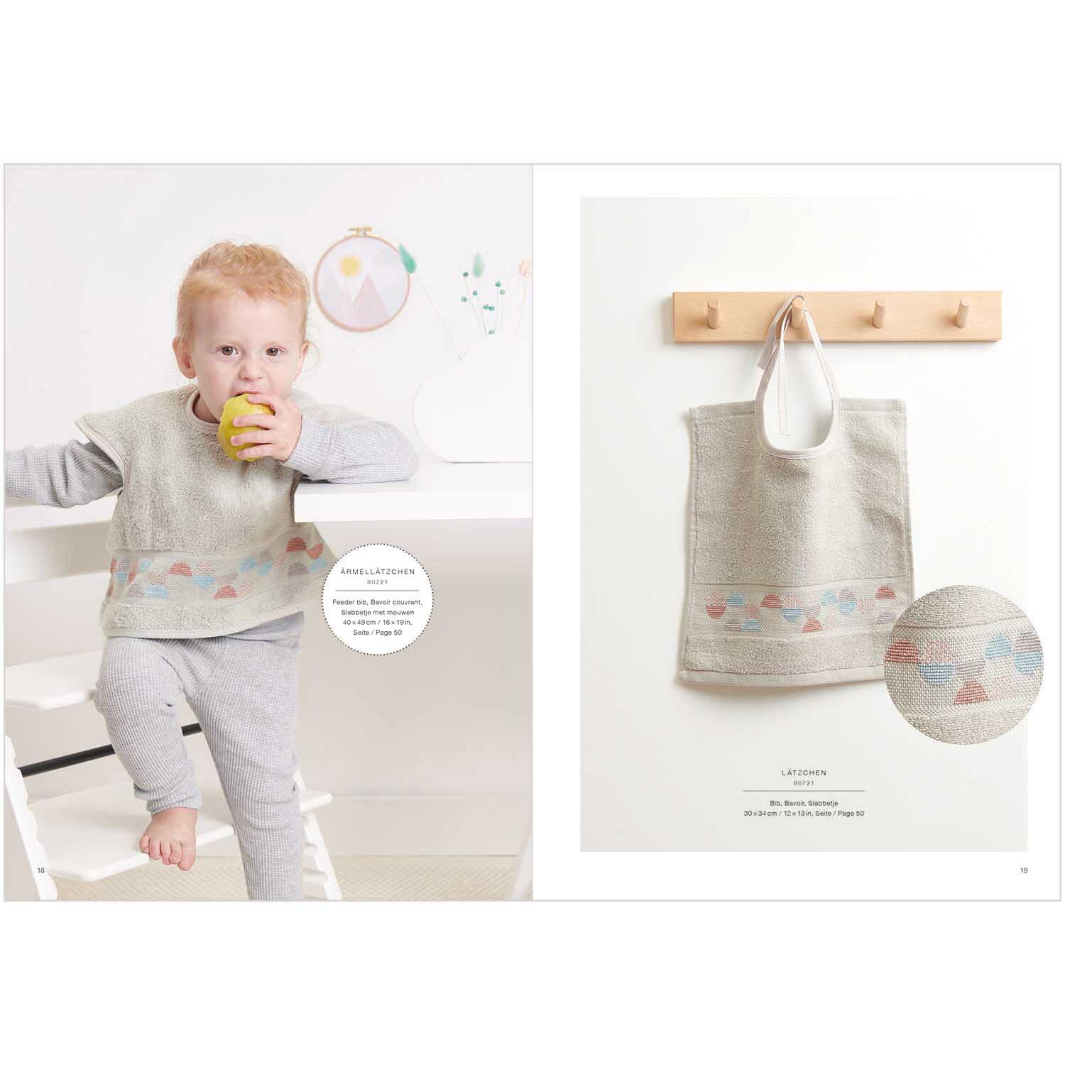Stickbuch Happy Baby Nr. 179: Kind in grauem Outfit mit buntem Muster, hält Apfel. Tasche mit ähnlichem Design an Haken.