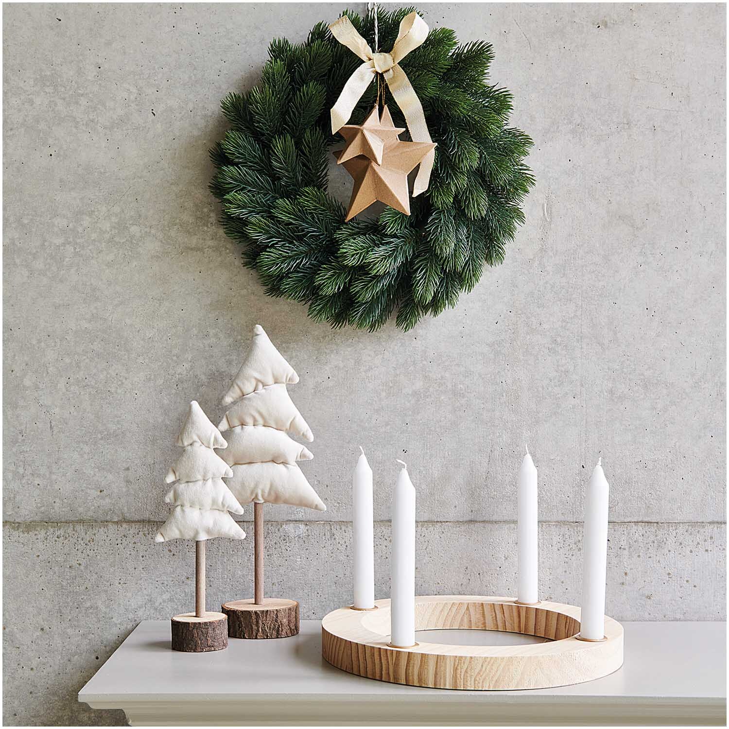 Adventskranz Holz natur: Eleganter Kranz mit grünen Zweigen und Holzstern, dekoriert auf einem Tisch mit weißen Kerzen und Stoffbäumen.