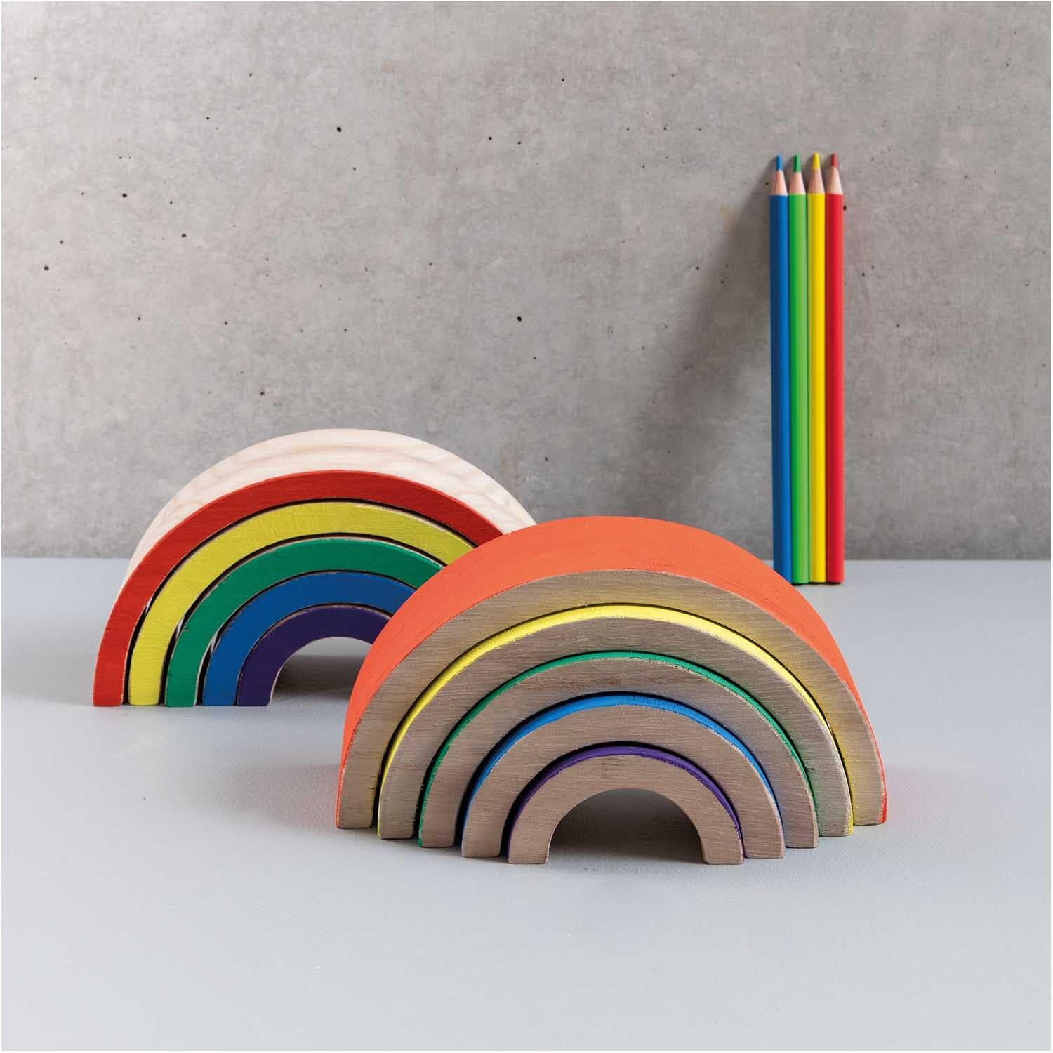 Holz-Regenbogen 18x9x5cm, 5-teilig. Bunte Holz-Bögen von Rico Design vor grauem Hintergrund, daneben farbige Stifte.