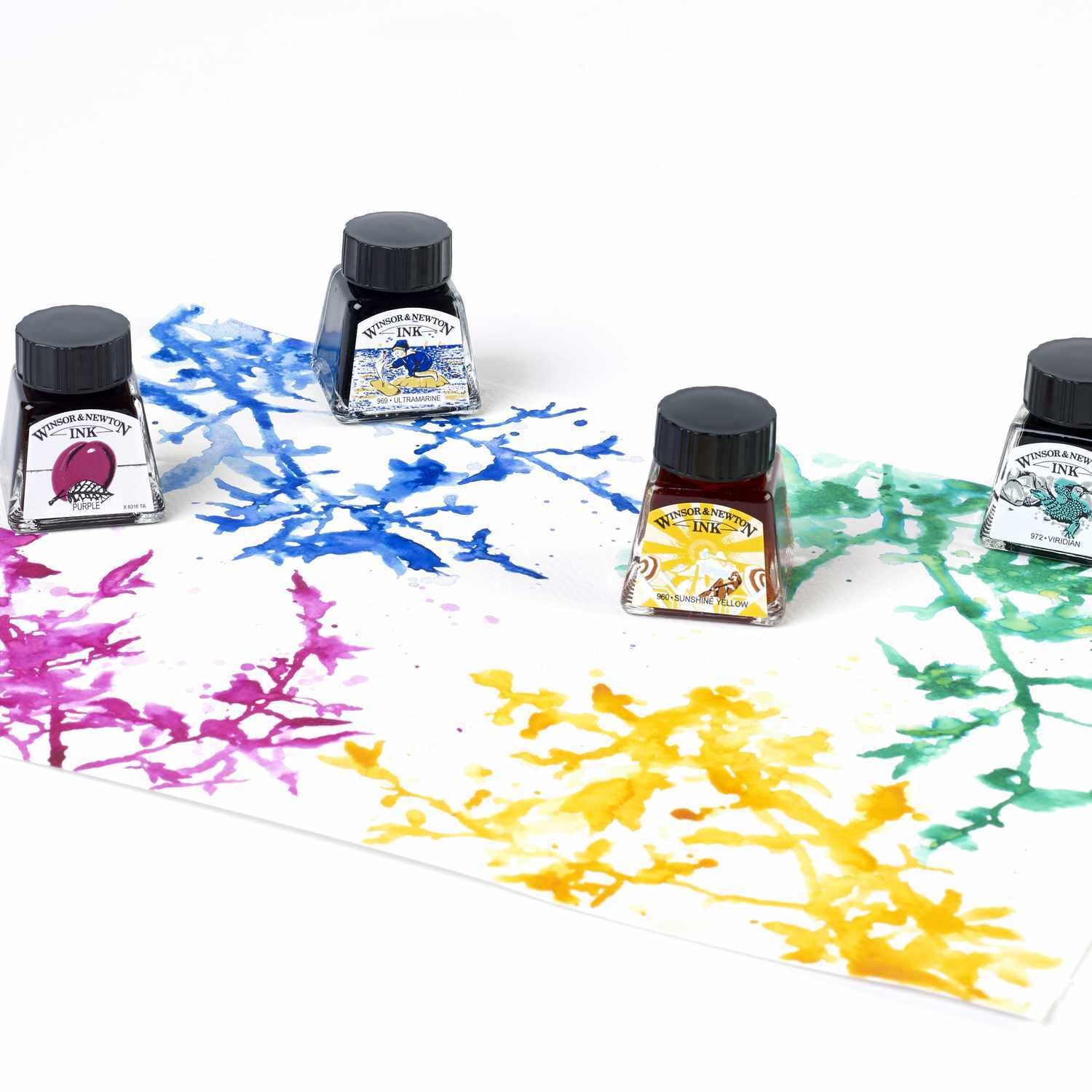 Zeichentusche 14ml von Winsor & Newton in verschiedenen Farben auf Papier verteilt, mit vier Tintenflaschen.