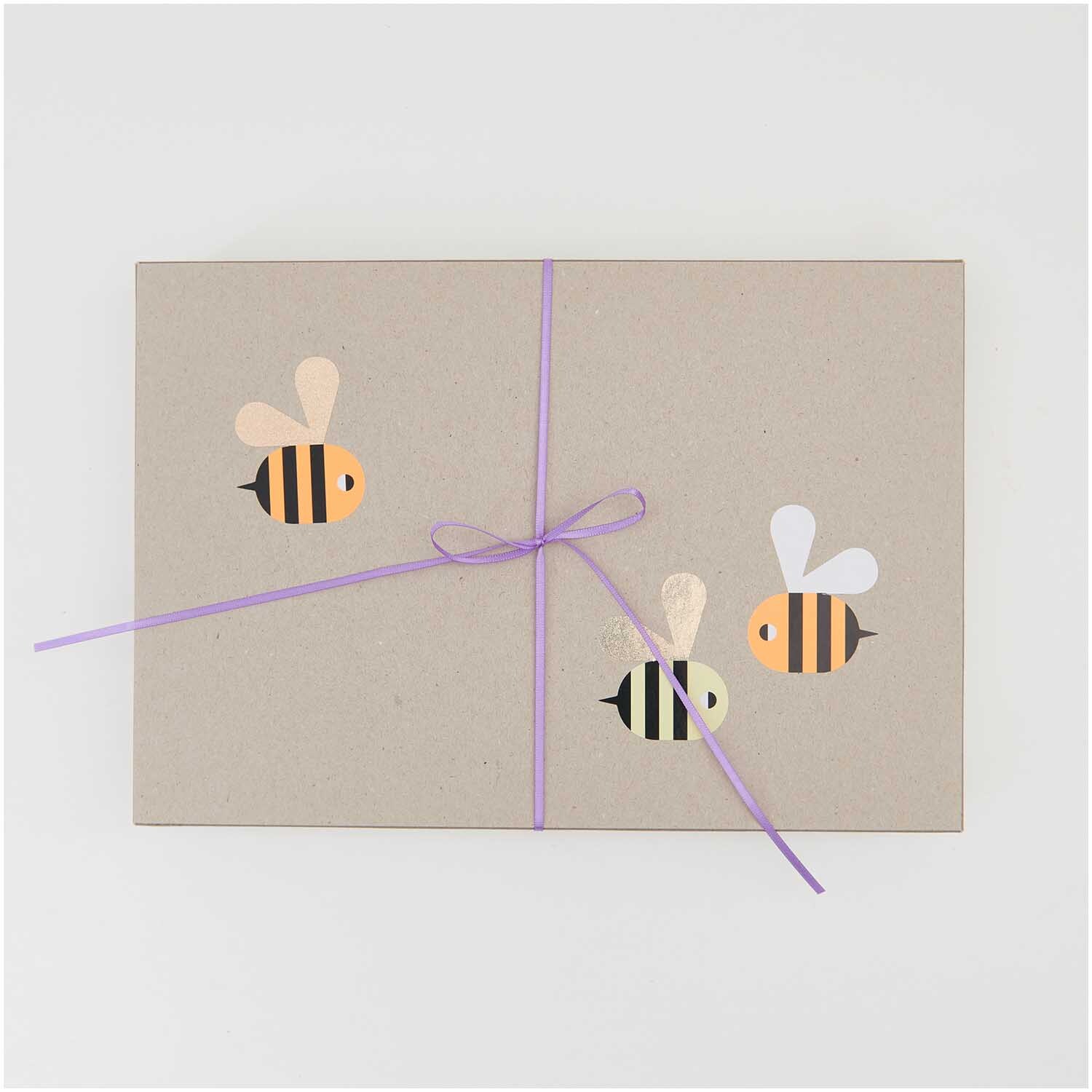 Paper Poetry Sticker Bienen Ø 5cm, 120 Stück von Rico Design auf Rolle, dekorieren eine graue Box mit lila Band.