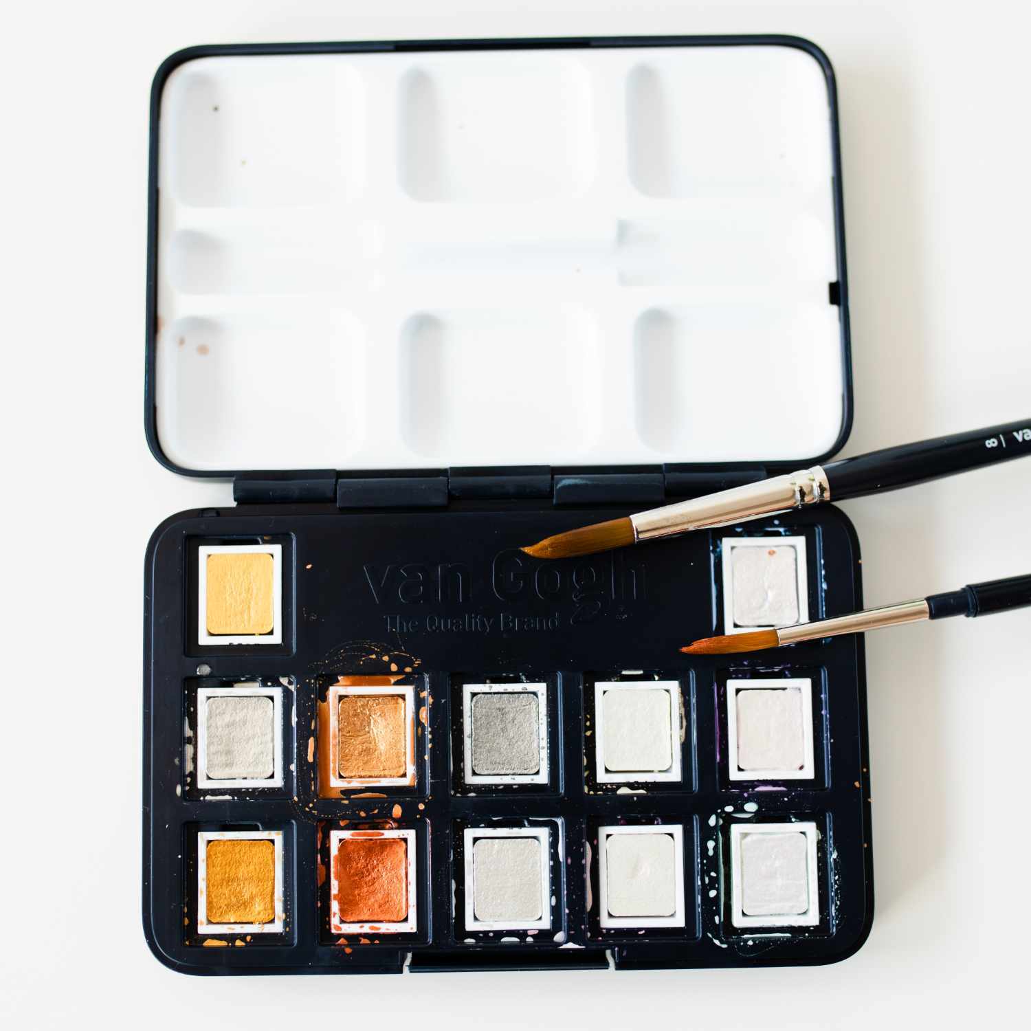 Aquarell Set Metallic Farben 12 Näpfchen mit Pinseln, präsentiert in einer offenen schwarzen Box.