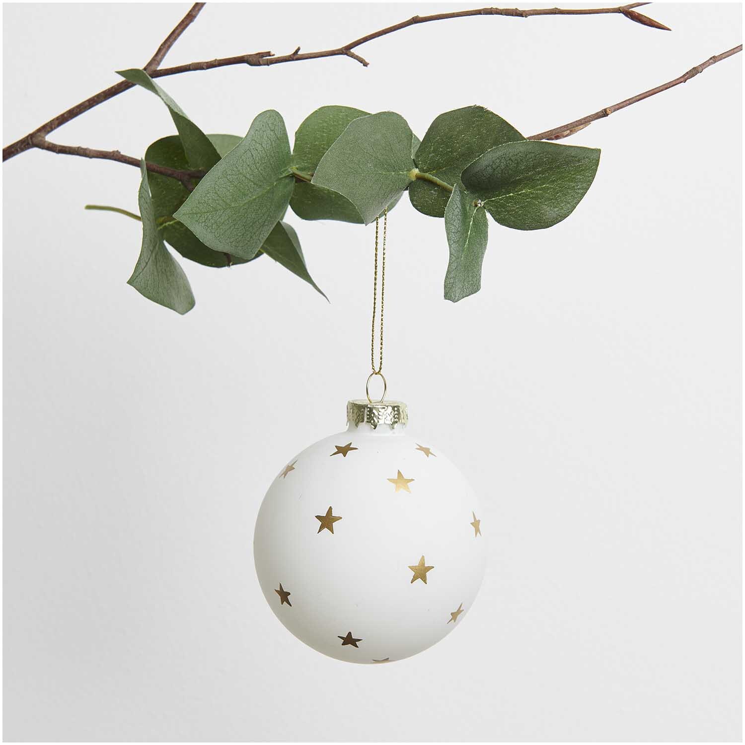 Glaskugel Baumschmuck mit Sterne, hängend an einem Ast, verziert mit goldenen Sternen.