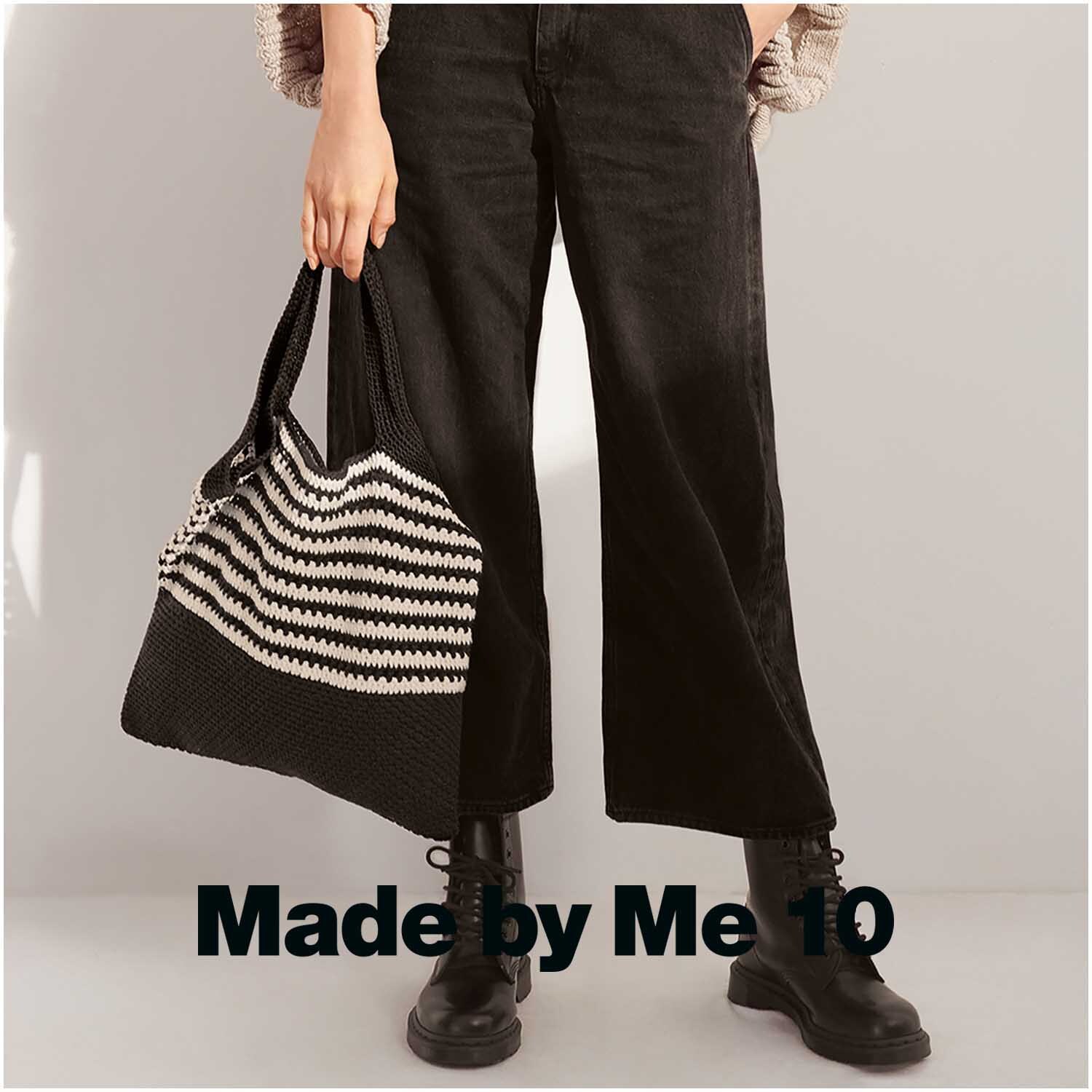 Creative Cotton aran: Person mit schwarzer Hose und Stiefeln hält gestreifte Tasche.