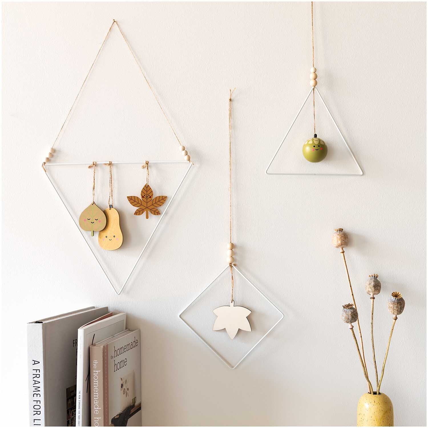 Holzhänger Eichel grün Ø 5cm von Rico Design an einer Wand, dekoriert mit minimalistischen Rahmen und Trockenblumen.