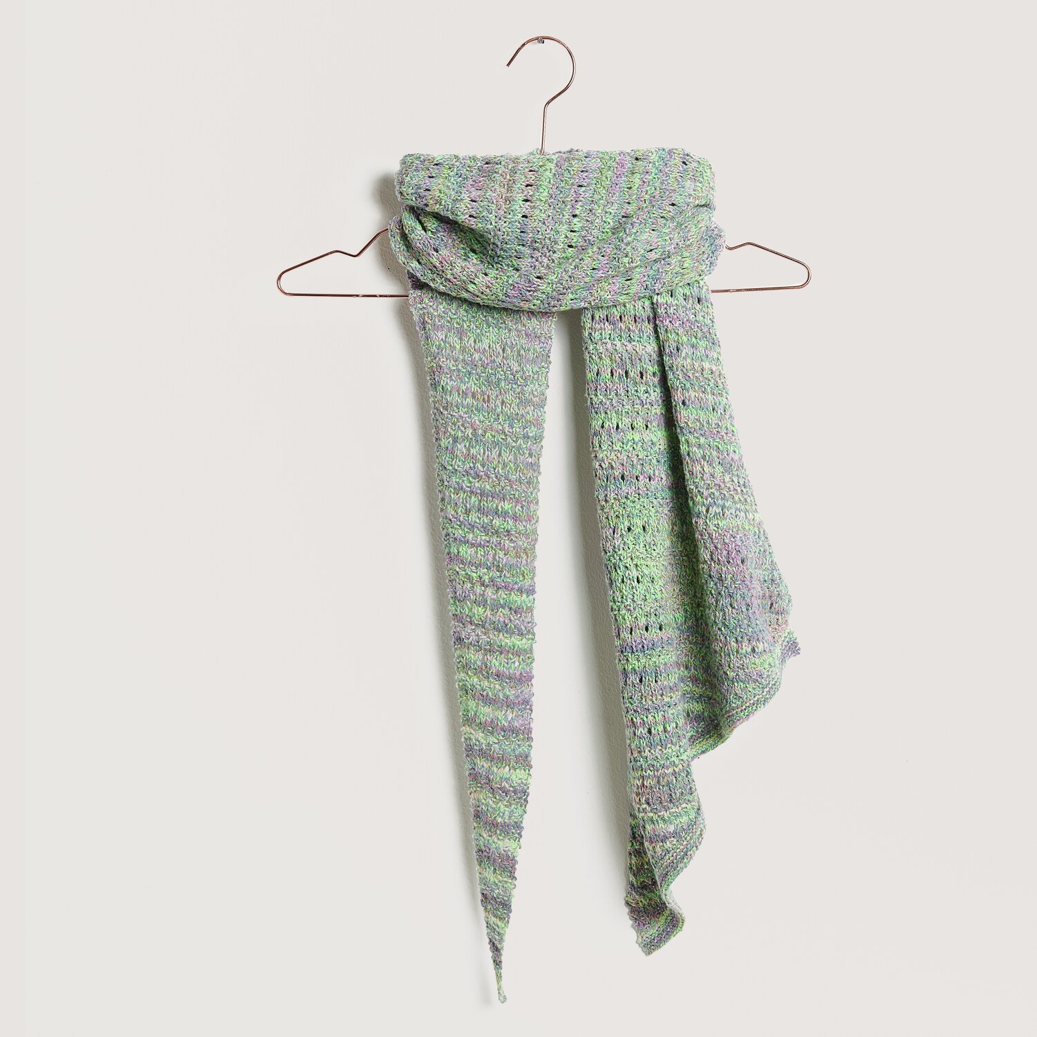 Strickset Dreieckstuch Modell 17 aus Lovewool No. 20, präsentiert auf einem Kleiderbügel. Das Tuch zeigt ein zartes Blumenmuster in Pastelltönen.