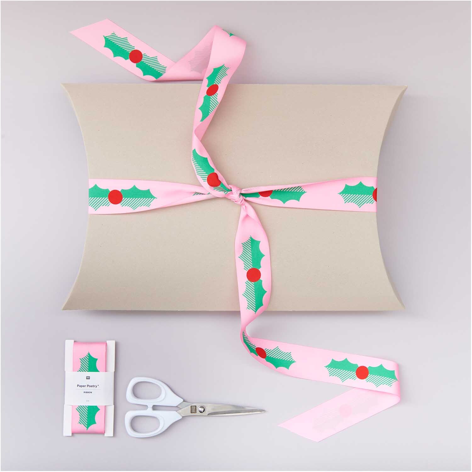 Paper Poetry Taftband Ilex 38mm 3m, rosa Geschenkband mit grünen Blättern und roten Beeren, dekoriert auf einer Geschenkbox.