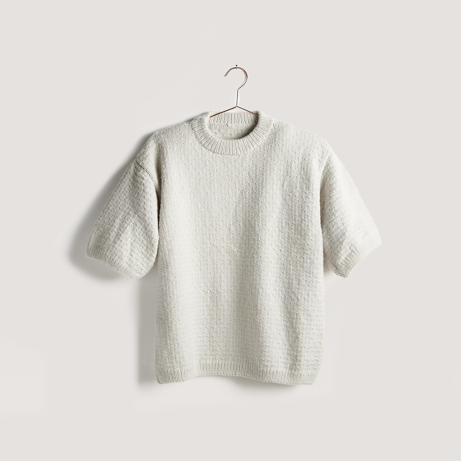 Strickset Shirt Modell 13a aus Vegan Cashmere in Creme von Rico Design, auf einem Bügel hängend.