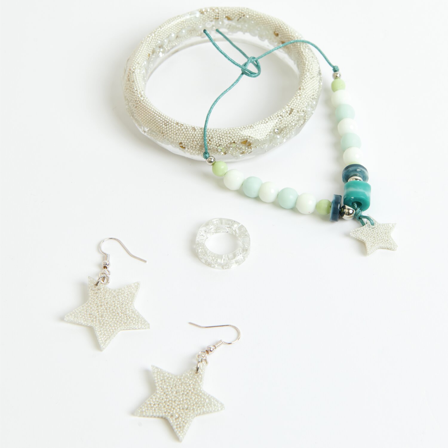 Füllmaterial für Resin Perlen, Diamanten, Kügelchen von Rico Design. Abgebildet sind ein Armband, Ohrringe und ein Ring in Silber.
