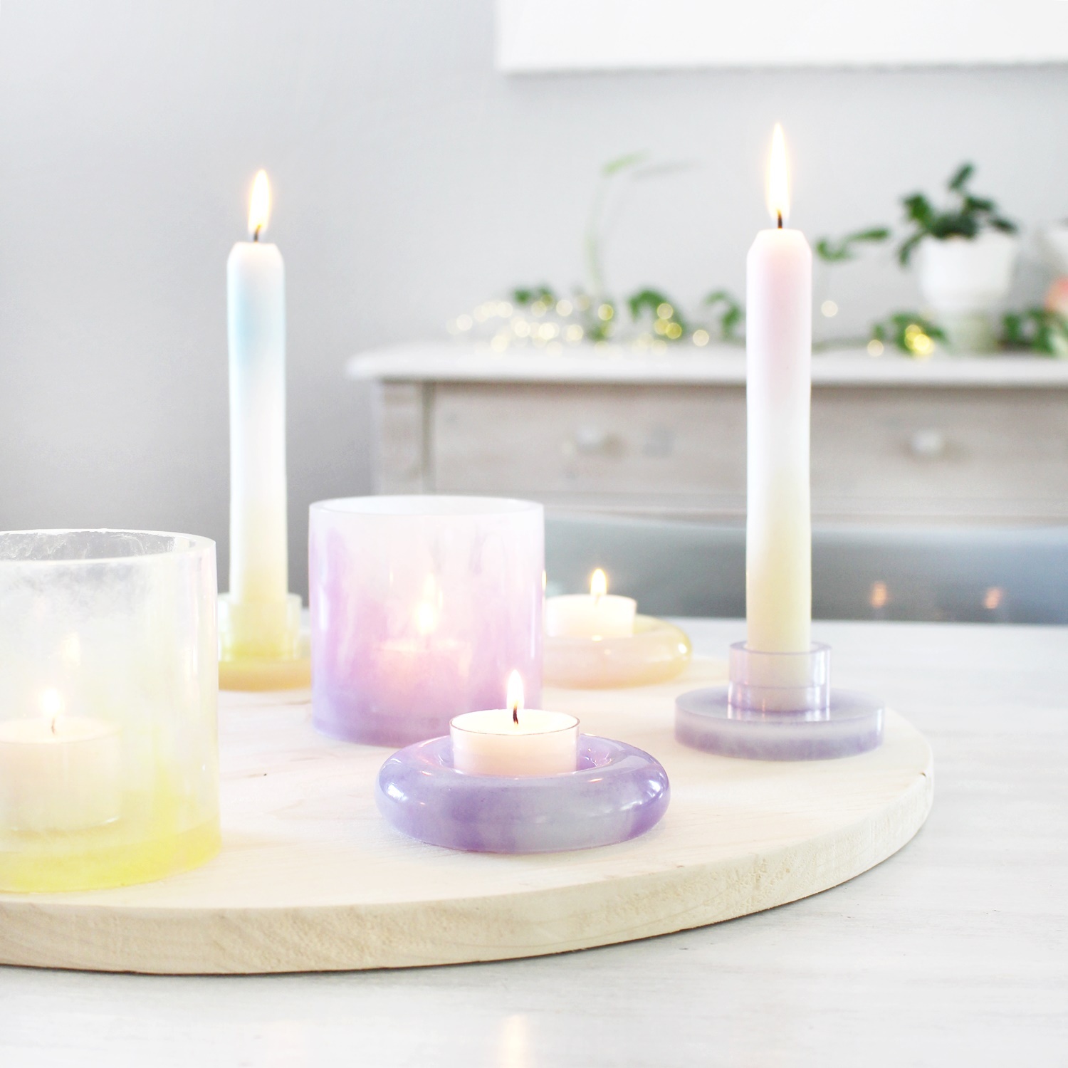 Inspiration Kerzenhalter aus Resin: Bunte Kerzen auf einem runden Holztablett, dekorativ arrangiert.