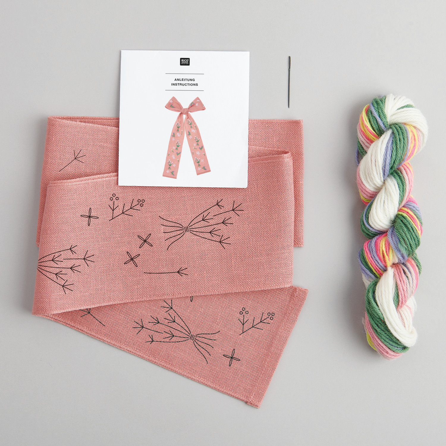 Stickpackung Schleife Frühlingsblümchen vorgezeichnet von Rico Design mit rosa Stoff, Nadel und buntem Garn.