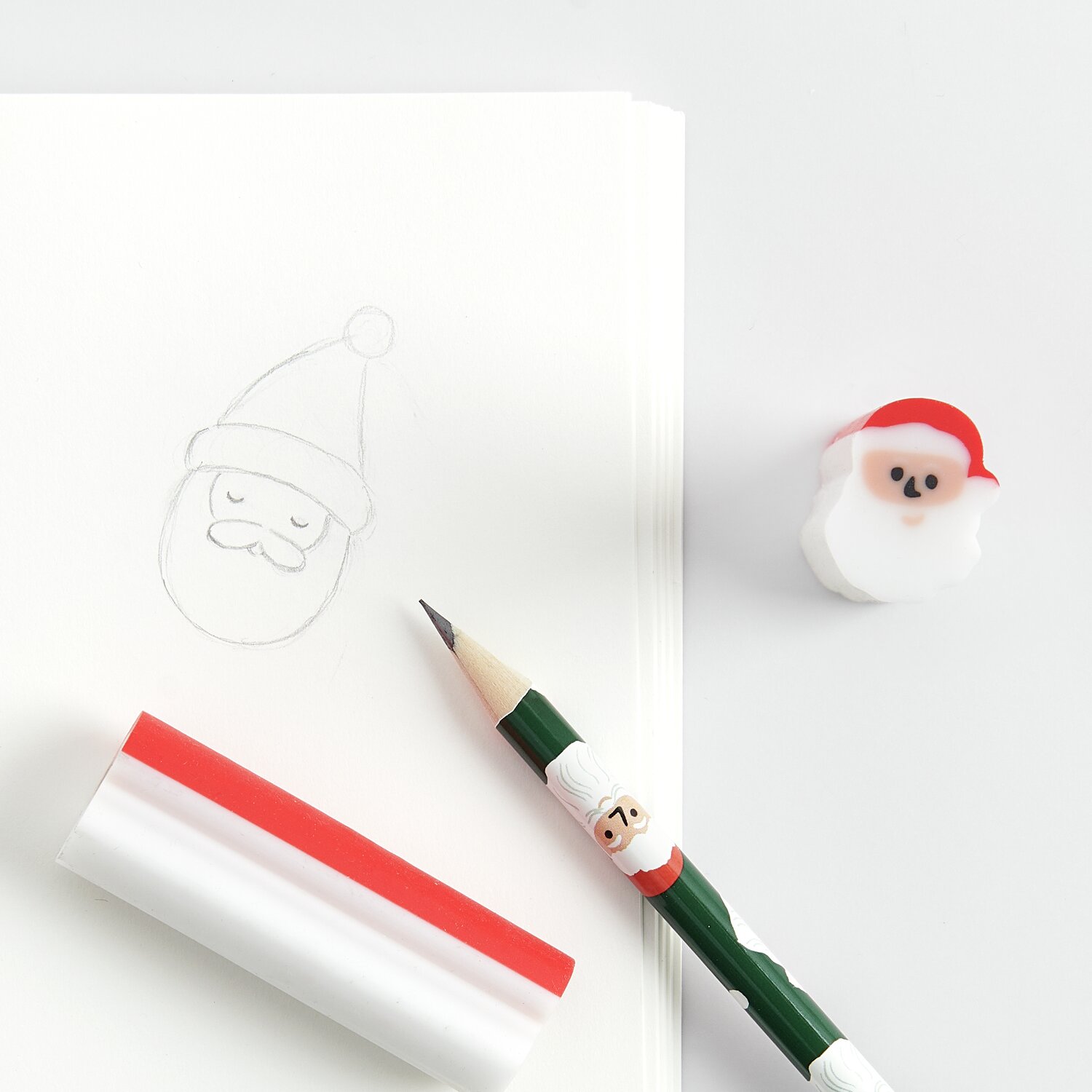 Display Paper Poetry Radiergummi Weihnachtsmann neben Bleistift und Skizze auf weißem Papier.