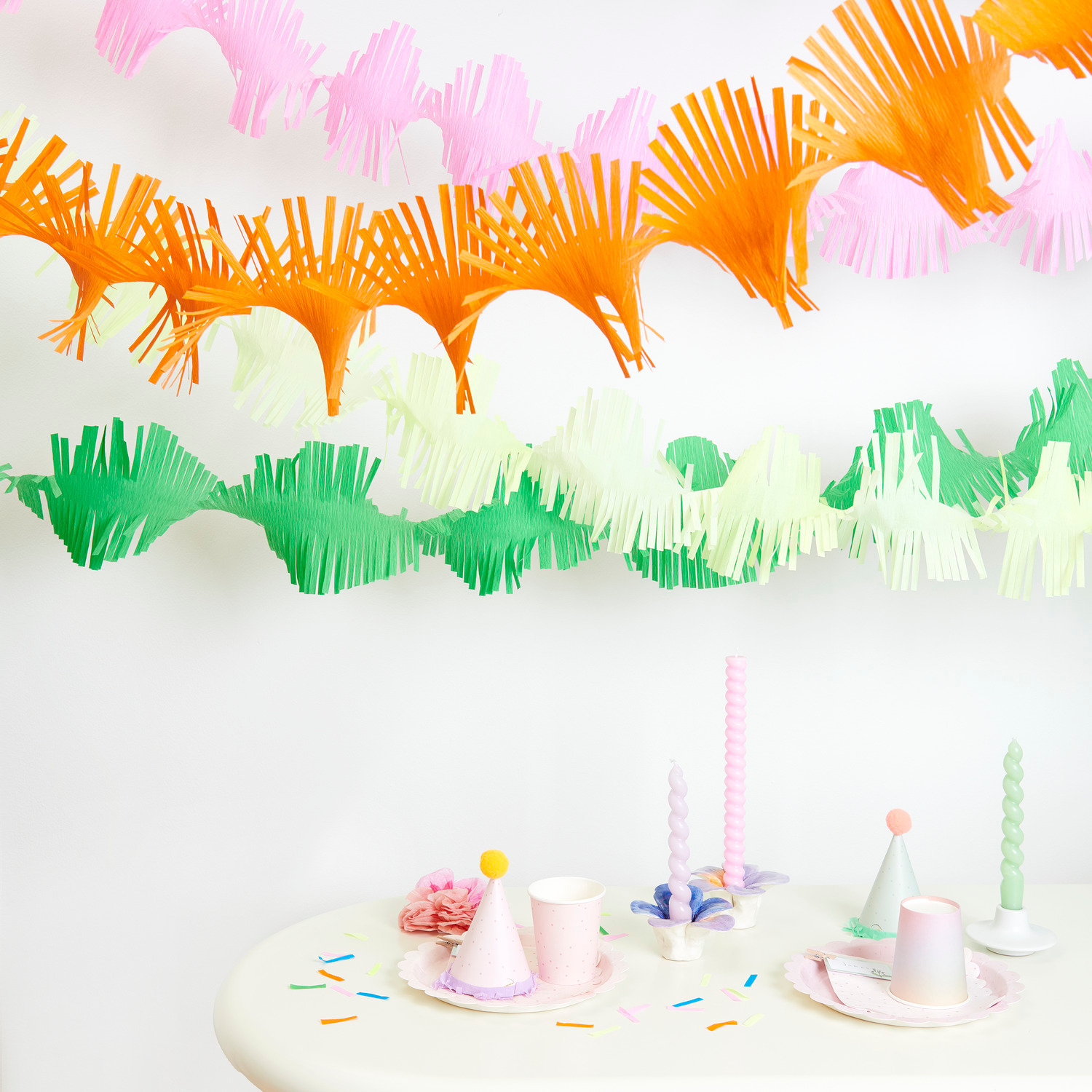 Krepp-Girlande gedreht Regenbogen Klassik Mix: Bunte Girlanden in Pastellfarben dekorieren einen Tisch mit Partyzubehör.