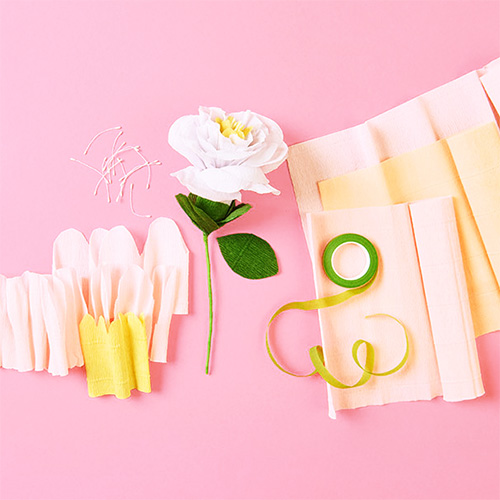 Eine Blume aus Krepppapier und Draht, daneben das dazugehörige Krepppapier.