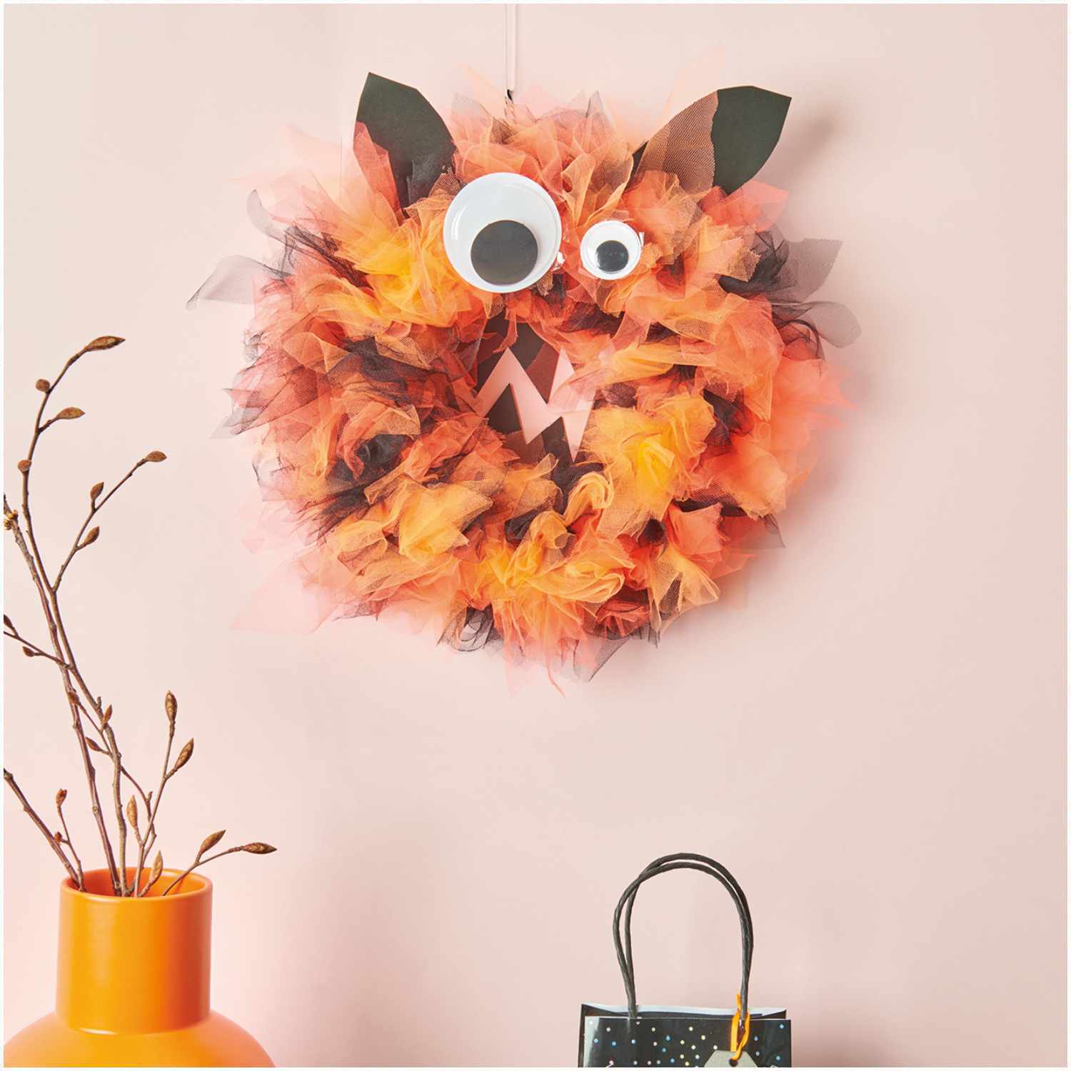 Bastelanleitung Halloween Monster-Kranz: Ein bunter Kranz mit großen Augen und Ohren an einer Wand. Perfekt für kreative Halloween-Dekorationen.