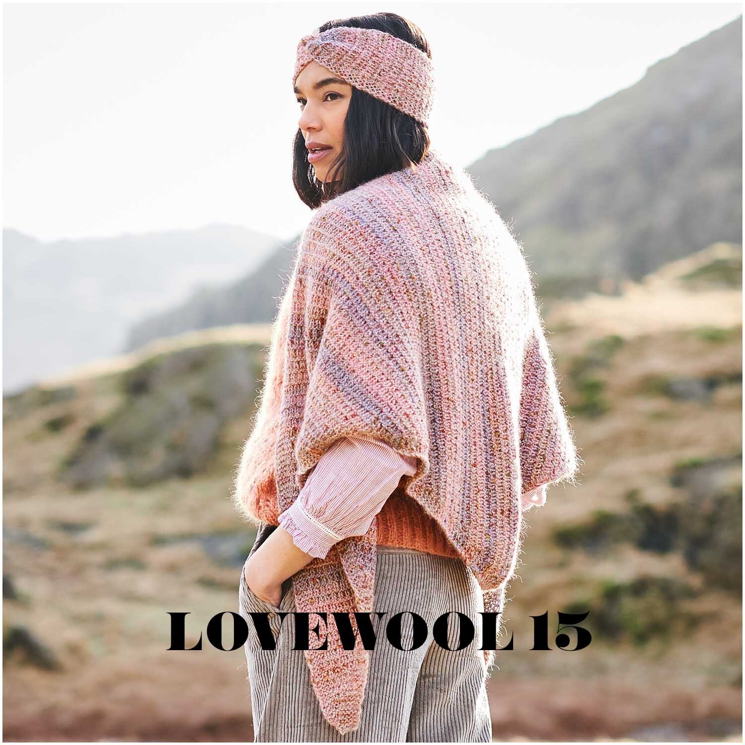 Creative Alpaca Melange aran: Frau trägt gestricktes Set aus Poncho und Stirnband in Pastellfarben von Rico Design in bergiger Landschaft.