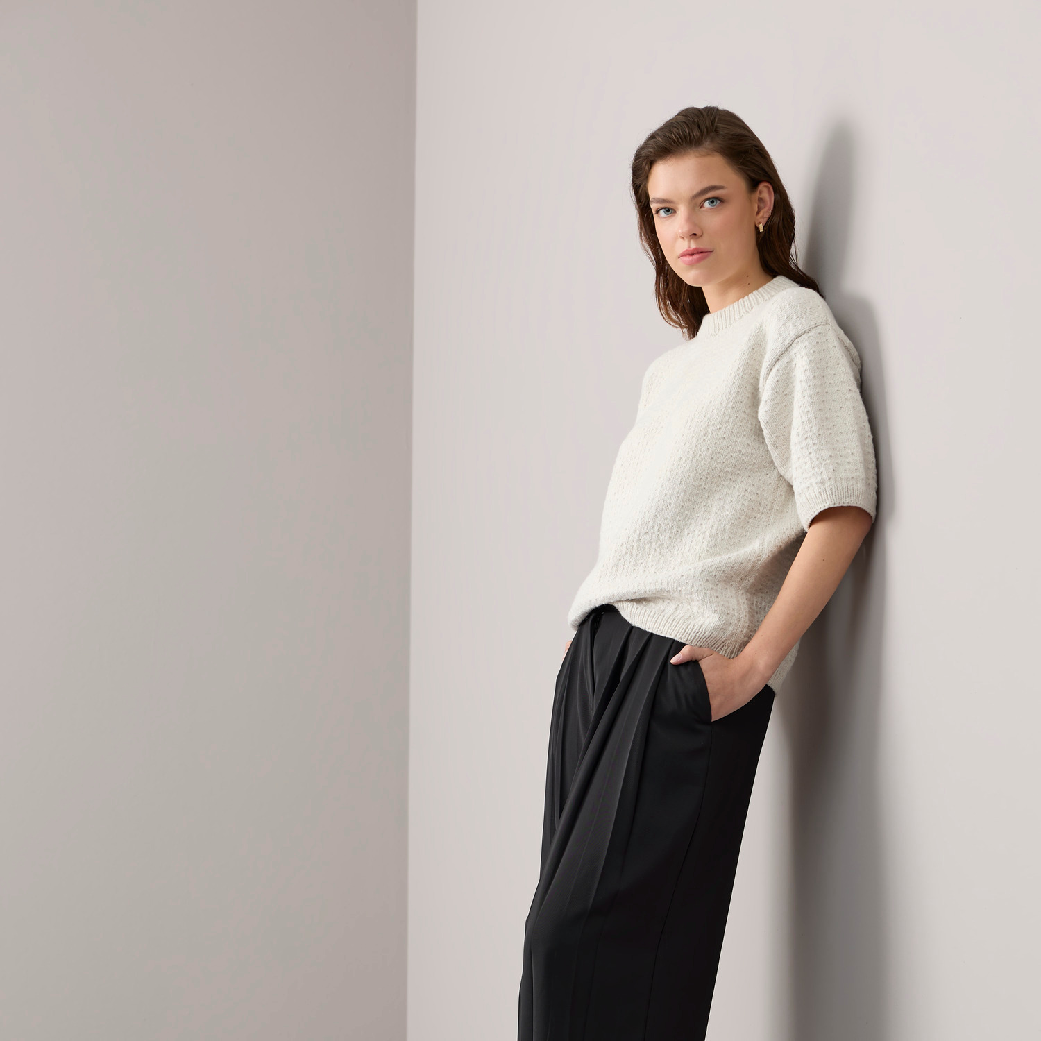 Strickset Shirt Modell 13a aus Vegan Cashmere in Creme von Rico Design, getragen von Frau an Wand.