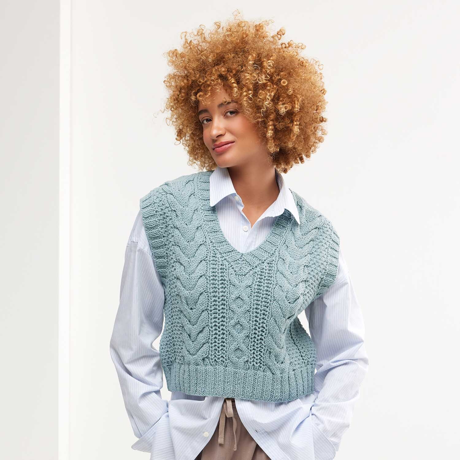 Strickanleitung Pullunder aus Classik: Frau trägt hellblauen Pullunder über weißem Hemd, lässiger Look.
