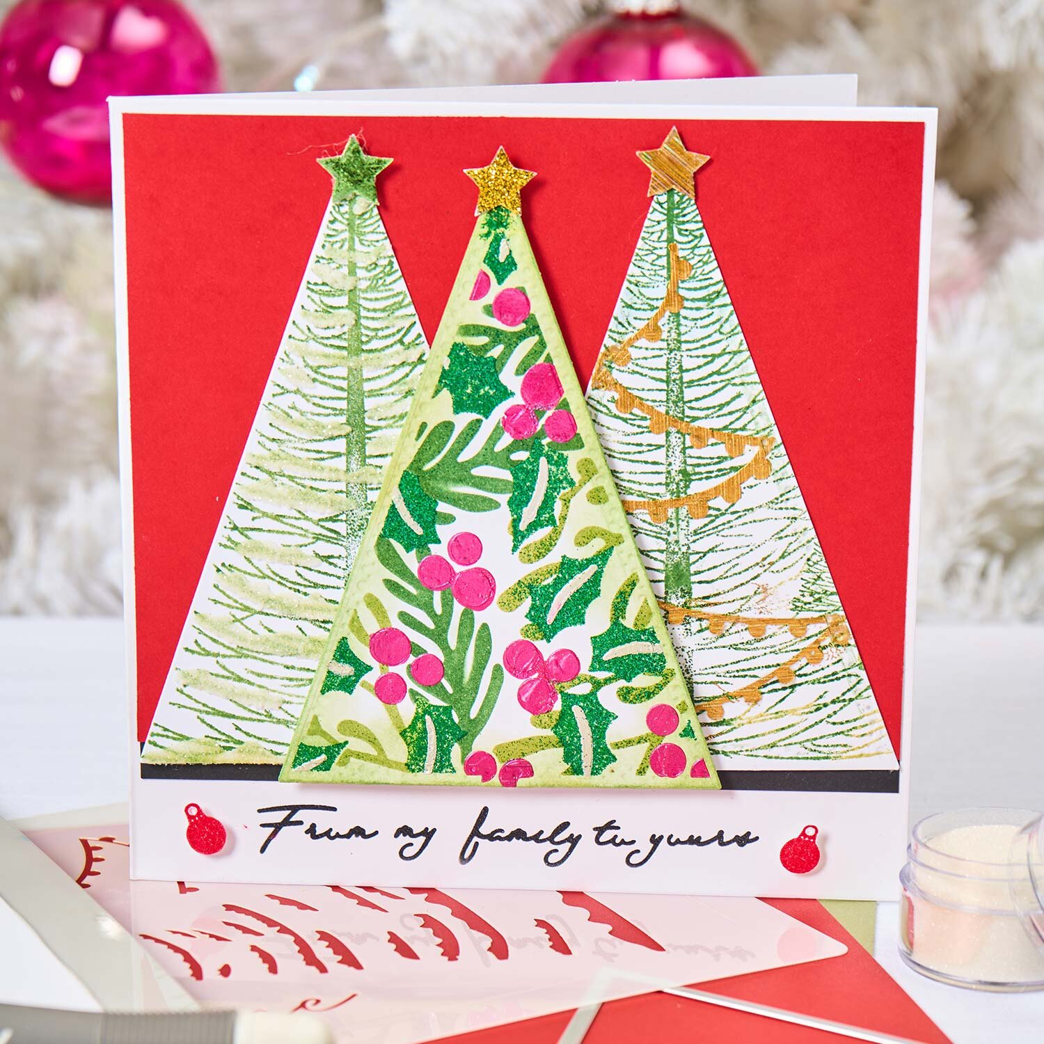 Sizzix Framelits Die Set Perfect Triangles: Drei bunte, weihnachtlich verzierte Dreiecke auf rotem Hintergrund.
