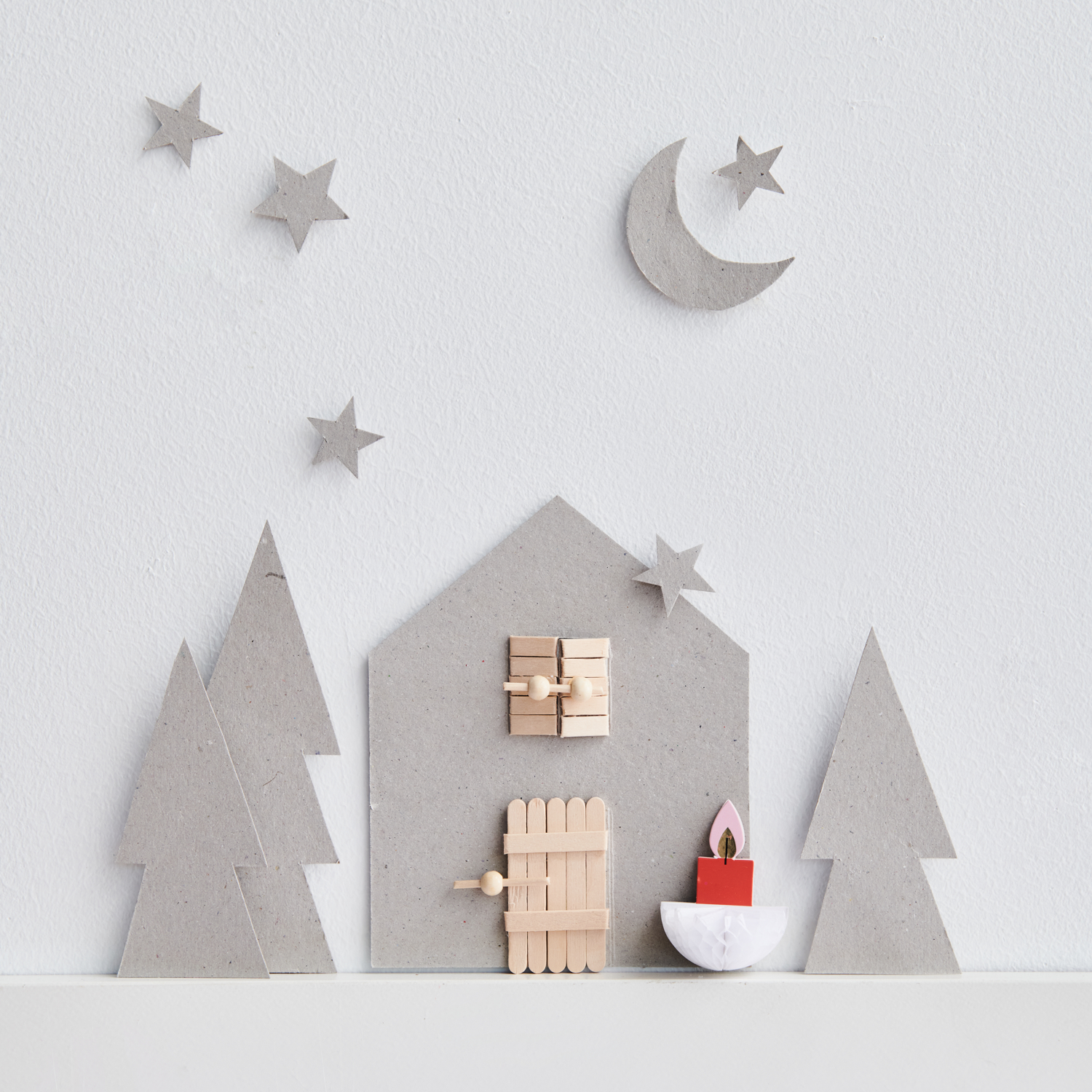 Bastelanleitung Wichtelhaus aus Pappkarton: Ein graues Haus mit Bäumen, Mond und Sternen aus Karton.
