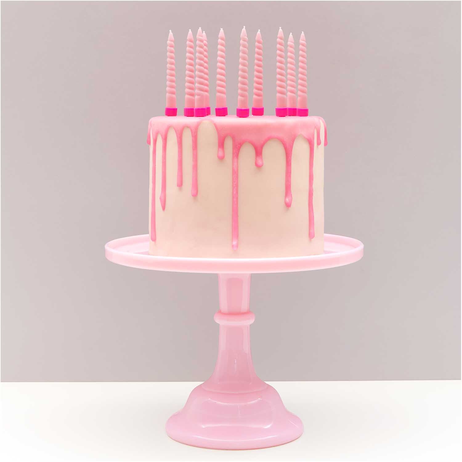 Spiralkerzen 1,2x10cm 10 Stück auf rosa Torte mit Tropfglasur, präsentiert auf rosa Tortenständer.