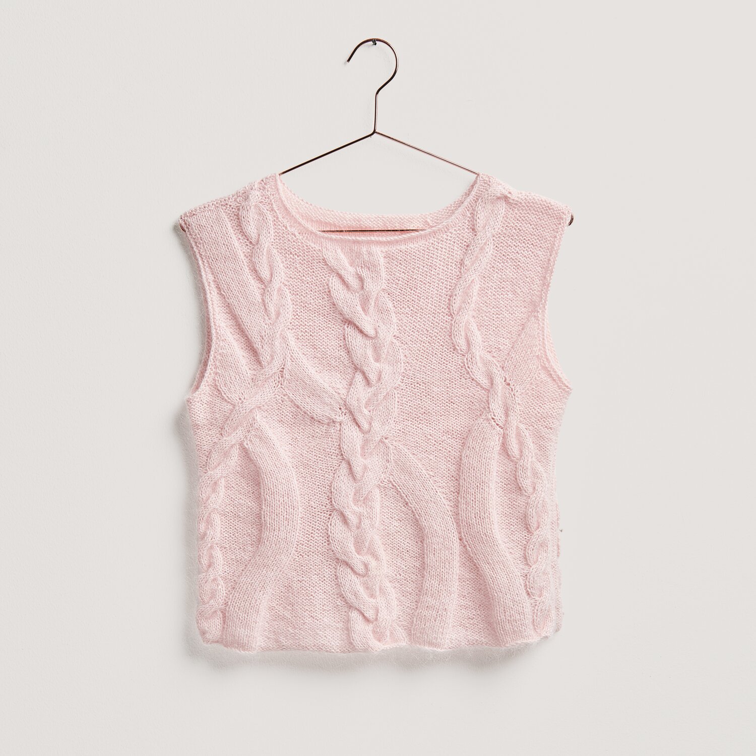 Strickset Top Modell 26 aus Lovewool No. 20: Rosa ärmelloses Oberteil mit Zopfmuster, präsentiert auf einem Kleiderbügel.