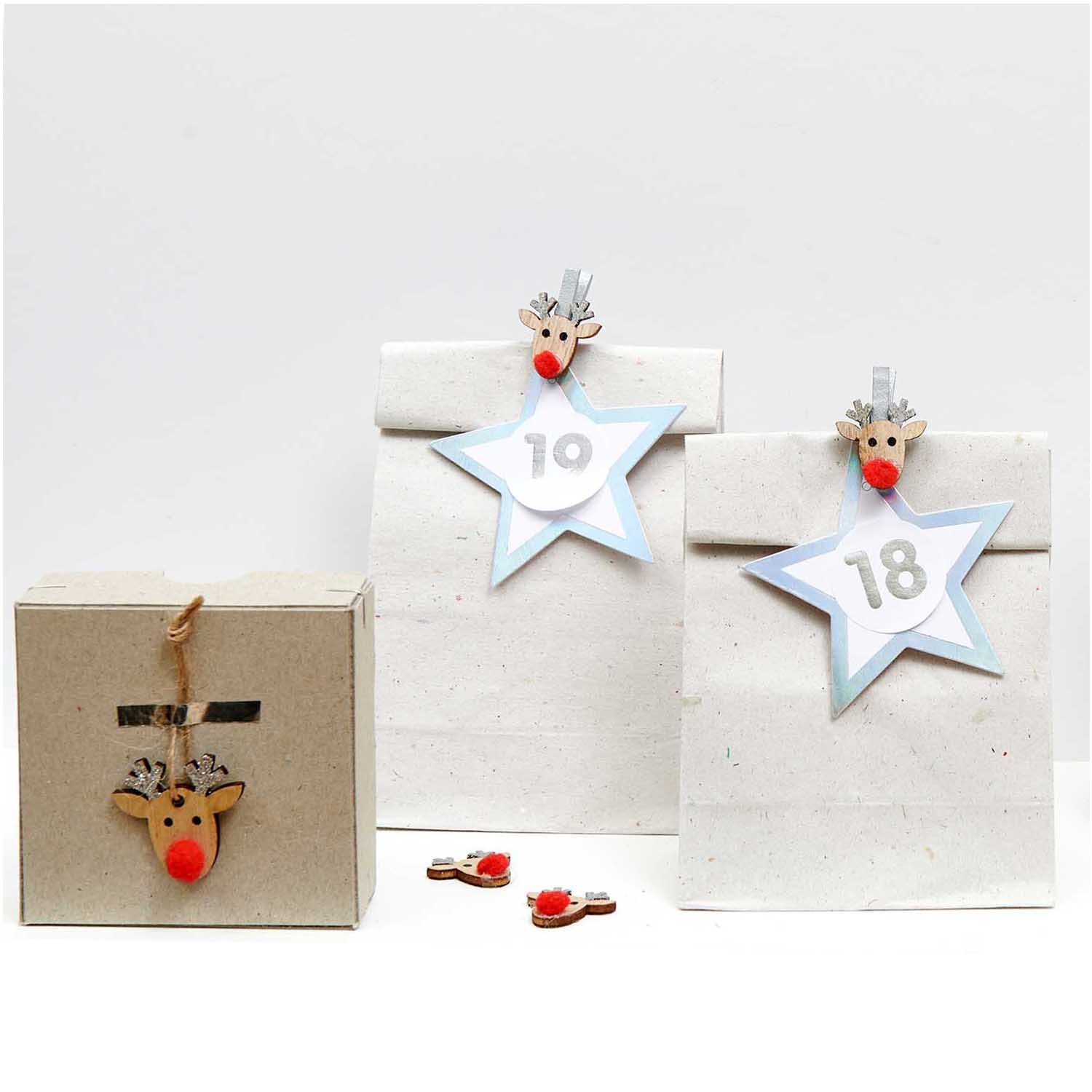 Paper Poetry Papieranhänger Stern in Silber von Rico Design, dekoriert mit Rentier-Clips auf Geschenktüten.