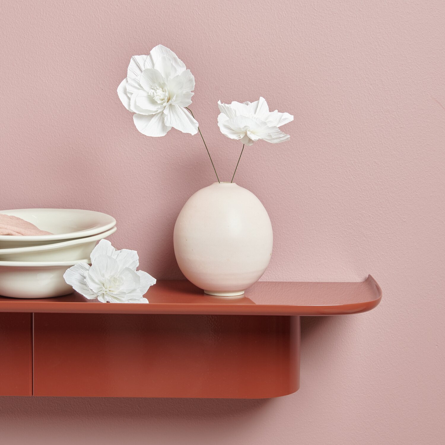 Krepppapier Blüten in Weiß von Rico Design in einer Vase auf einem rosa Regal arrangiert.