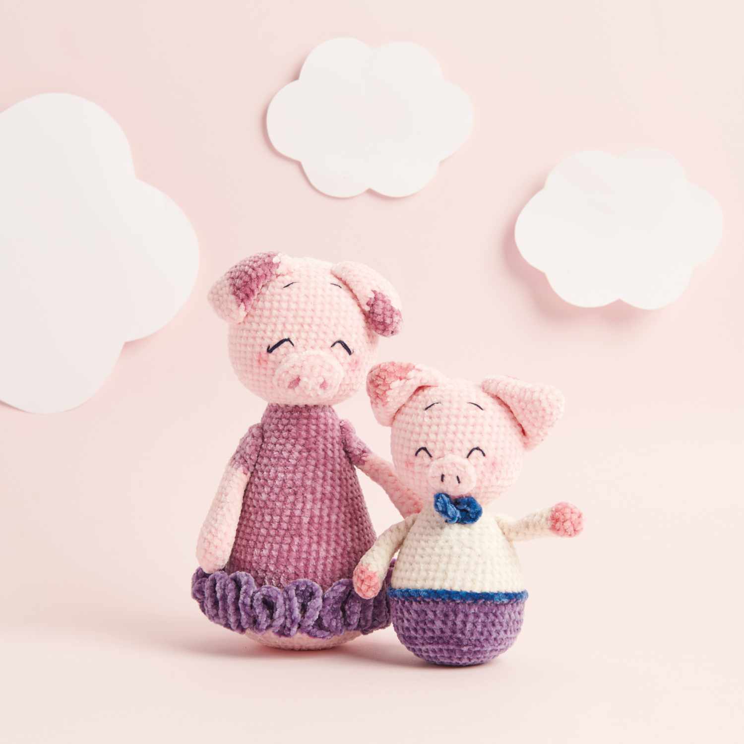 Häkelset Mama Schweinchen und Pepe aus Ricorumi Mini Me: Zwei gehäkelte Schweinchen vor rosa Hintergrund mit Wolken.