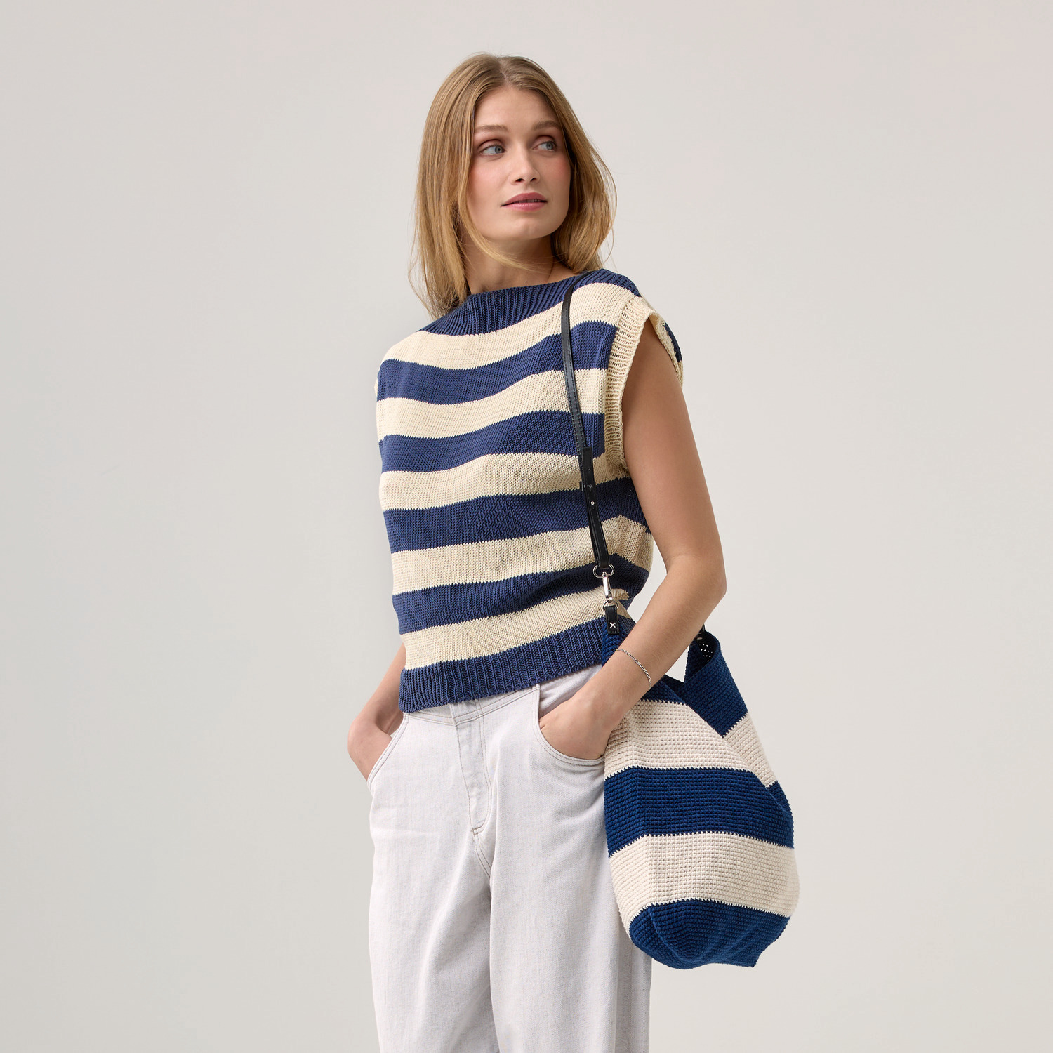 Die Neue Masche Nr. 09 Frühjahr-Sommer: Frau trägt gestreiftes Oberteil und Tasche in Blau und Weiß von Wolle Rödel.