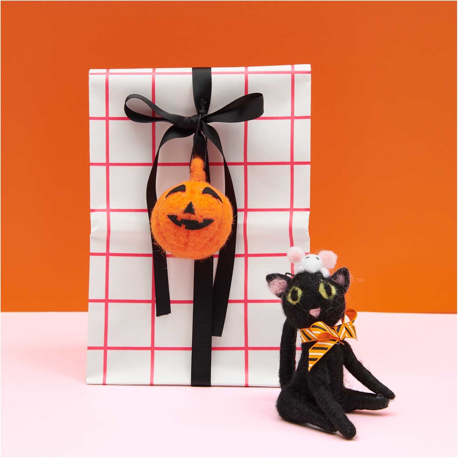 Katze mit Maus handgefilzt schwarz 8x12cm von Rico Design vor Geschenk mit Kürbis-Deko.