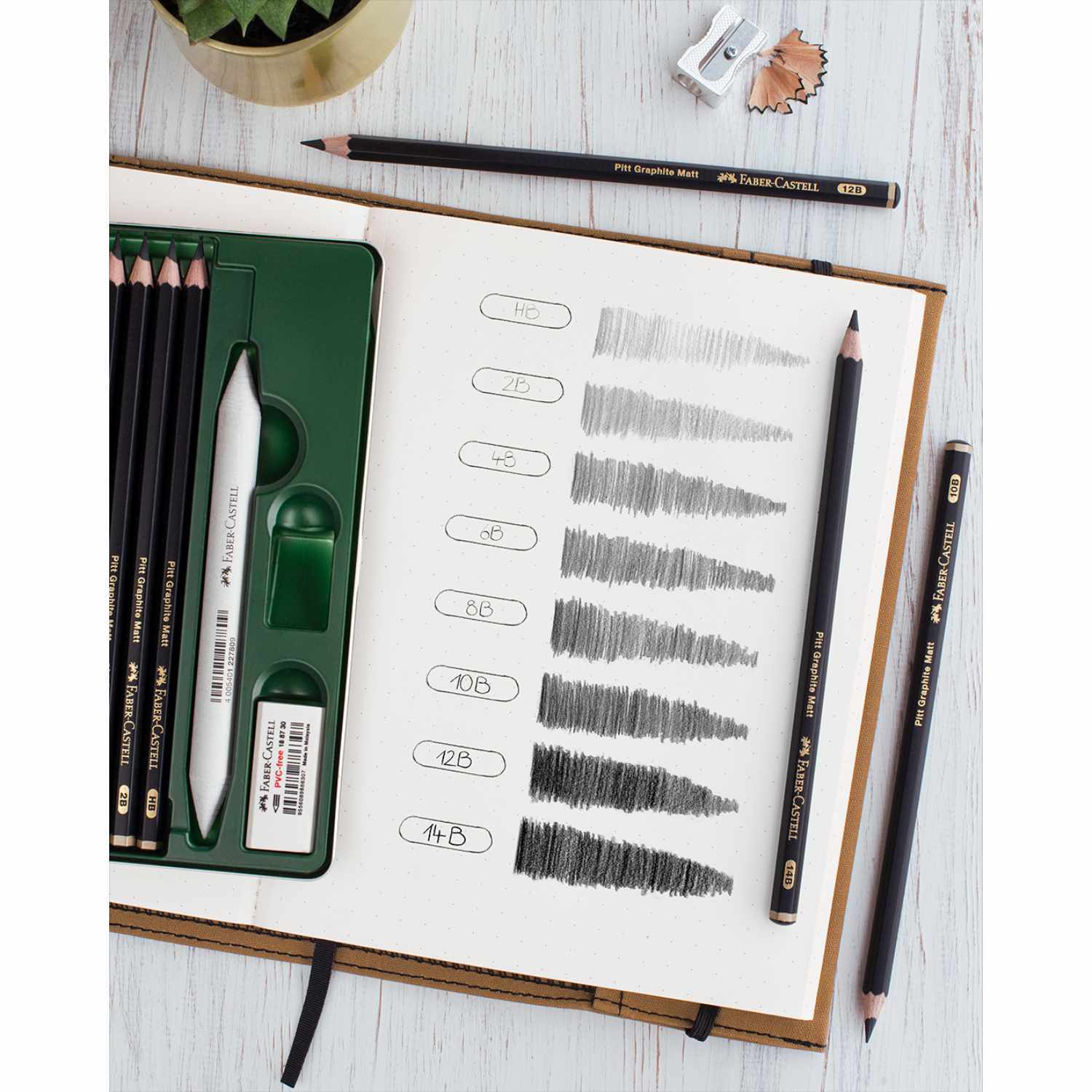 Bleistifte Pitt Graphite Matt, 11-teiliges Set von Faber Castell, auf einem Tisch mit Skizzenbuch und Zeichnungen.