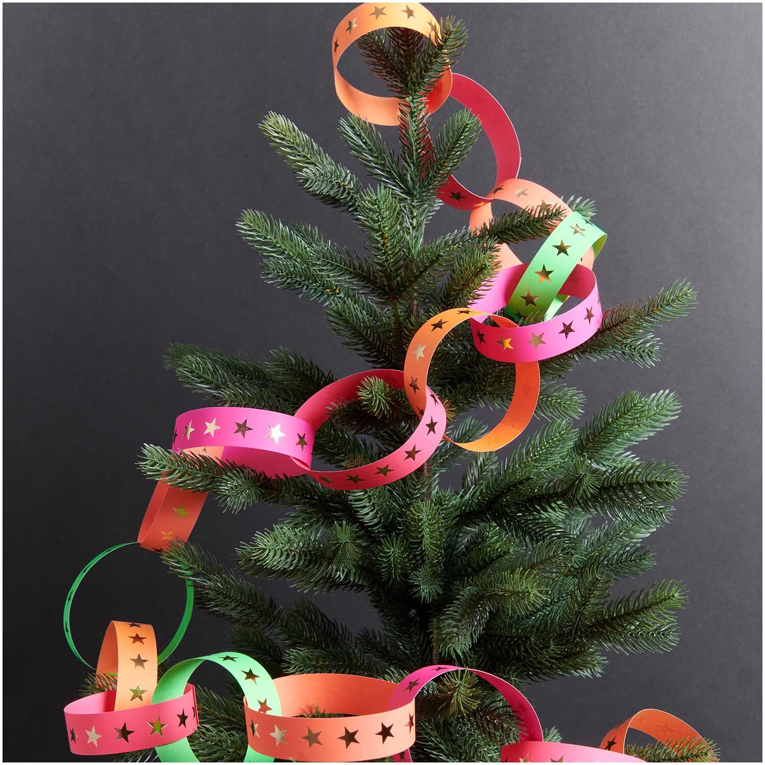 Paper Poetry Fröbelstreifen neon Sterne L 40 Stück schmücken einen Baum mit bunten Papierketten.
