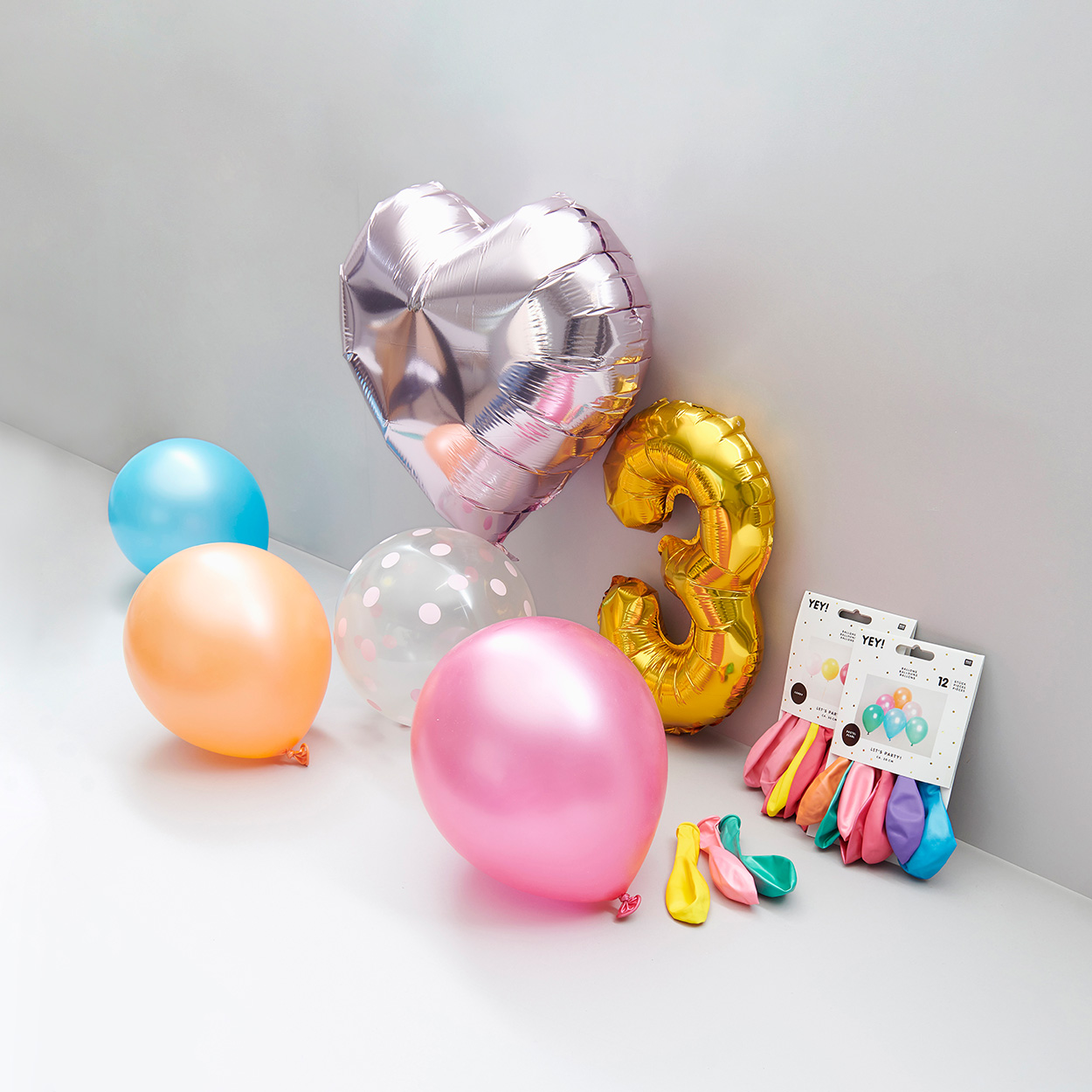 Aufgeblasene Luft- und Folienballons und Luftballons in Verpackung. Fotosetting graue Ecke.