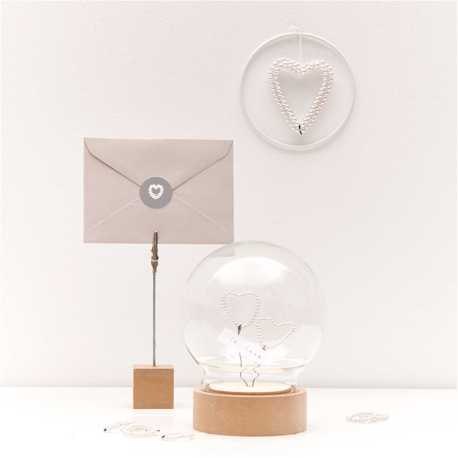 Perlenstreu Herz perlmutt 12 Stück von Rico Design: Dekoratives Herz aus Perlen in einem modernen, minimalistischen Arrangement mit Brief und Glaskugel.