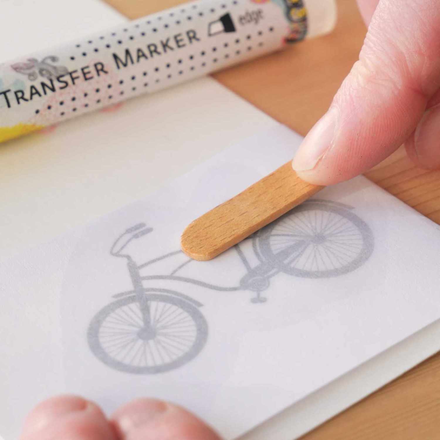 Transfer Marker von KREUL wird verwendet, um ein Fahrradbild auf Papier zu übertragen. Eine Hand hält einen Holzstab.