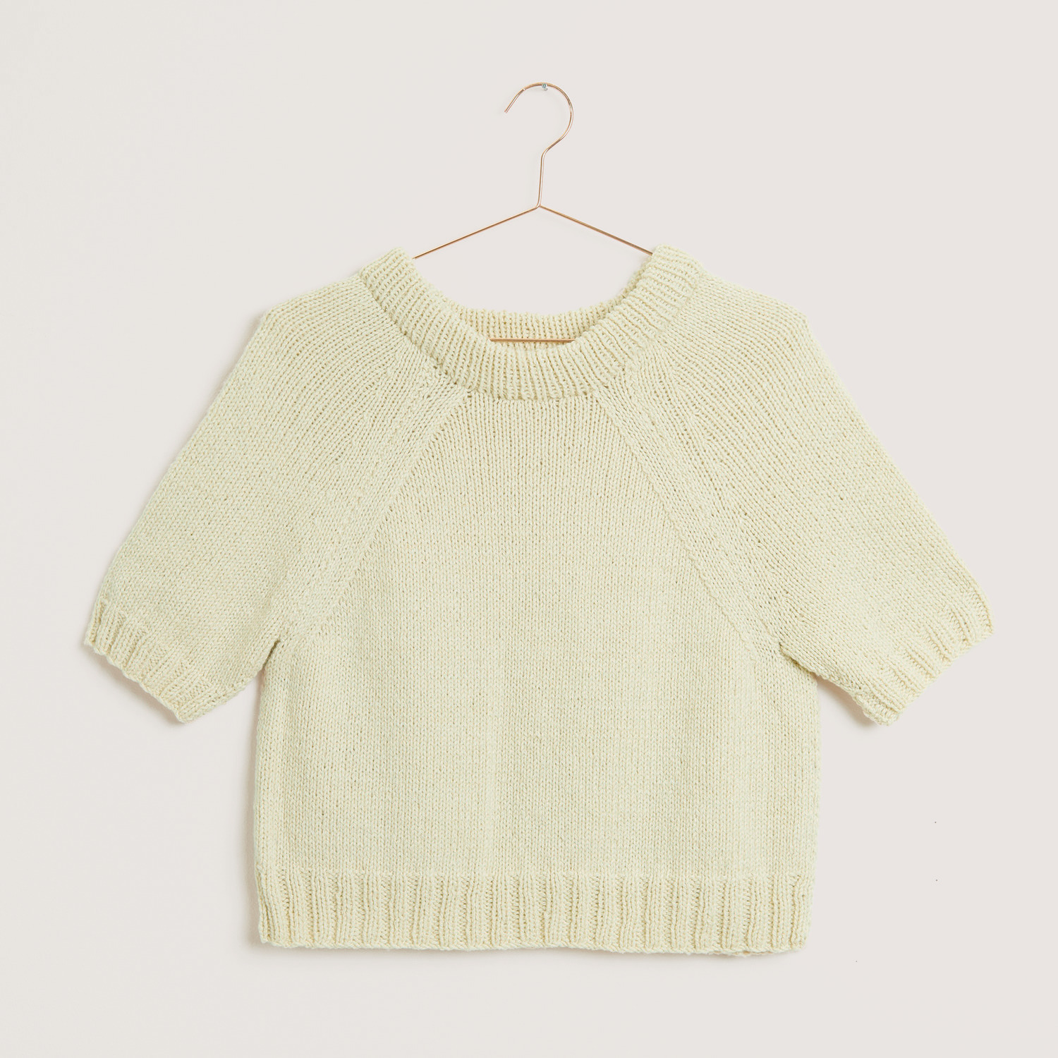 Luxury Natural Silk Blend, cremefarbener Strickpullover von Rico Design, kurzärmelig, auf einem Kleiderbügel präsentiert.