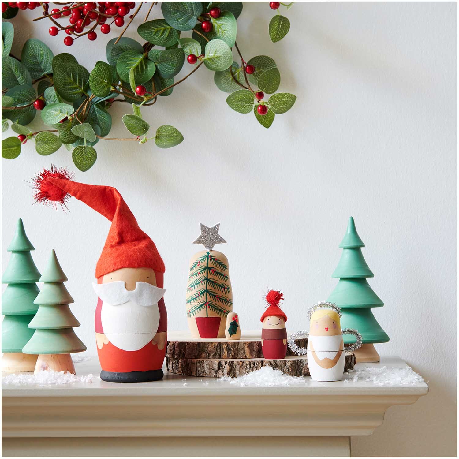 Deko-Tanne aus Holz grün: Weihnachtliche Szene mit grünen Holzbäumen und Figuren auf einem Kaminsims.